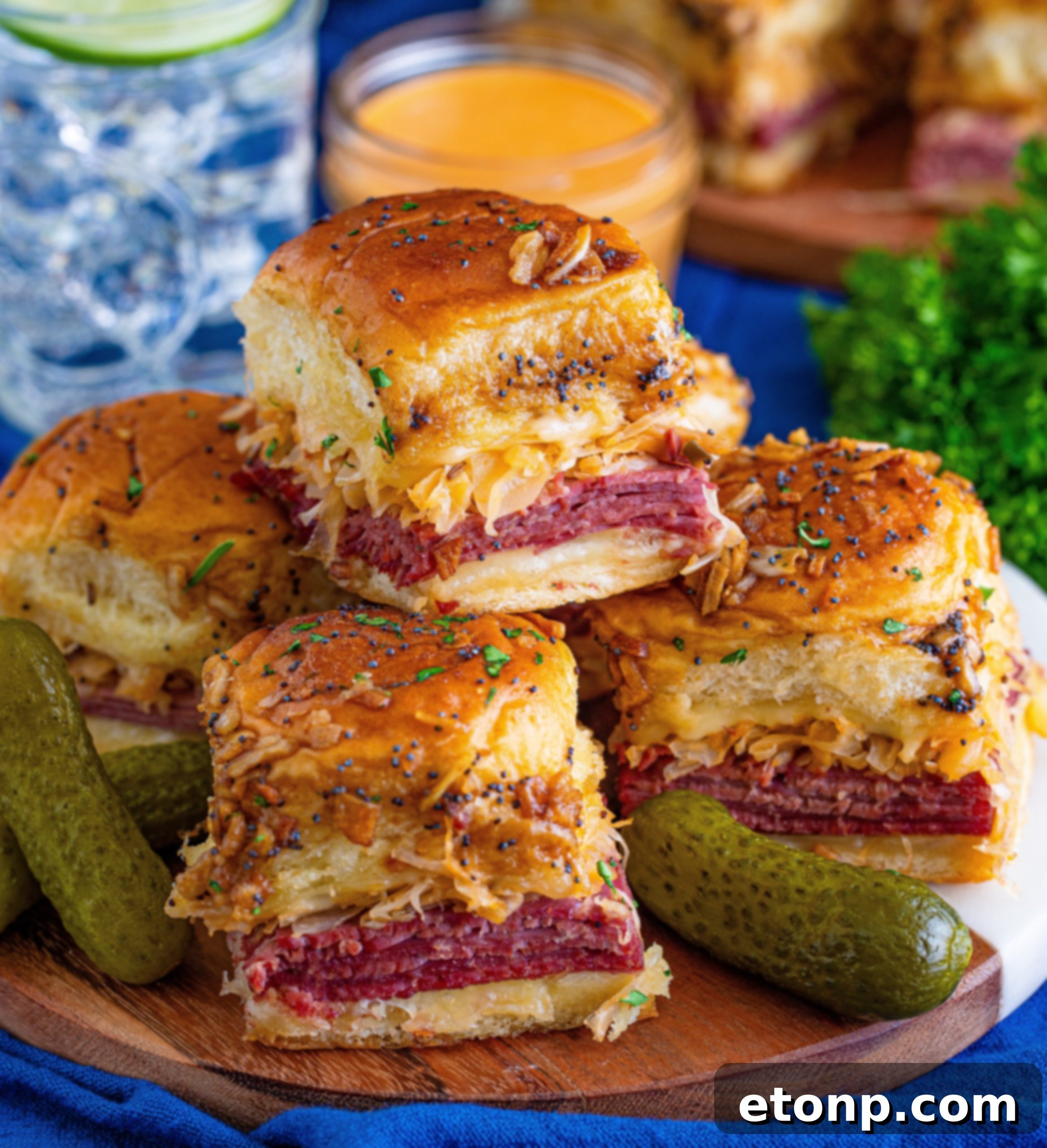 Mini Reuben Sandwiches 12 Reuben Sliders ready for serving, beautifully garnished with fresh herbs and a small bowl of extra dressing on the side.