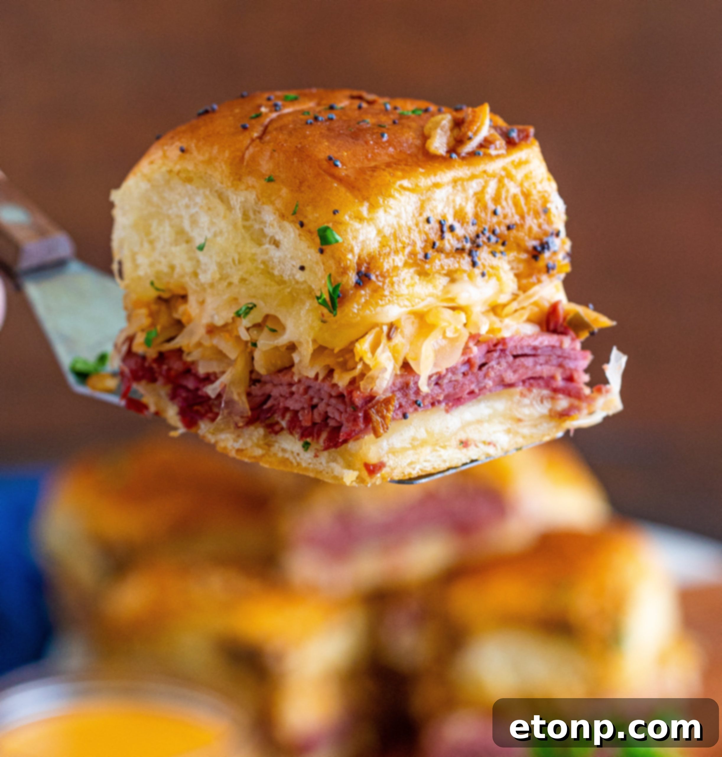 Mini Reuben Sandwiches 7 Ingredients for Reuben Sliders laid out on a cutting board, including thinly sliced corned beef, Swiss cheese, sauerkraut, and soft Hawaiian rolls.
