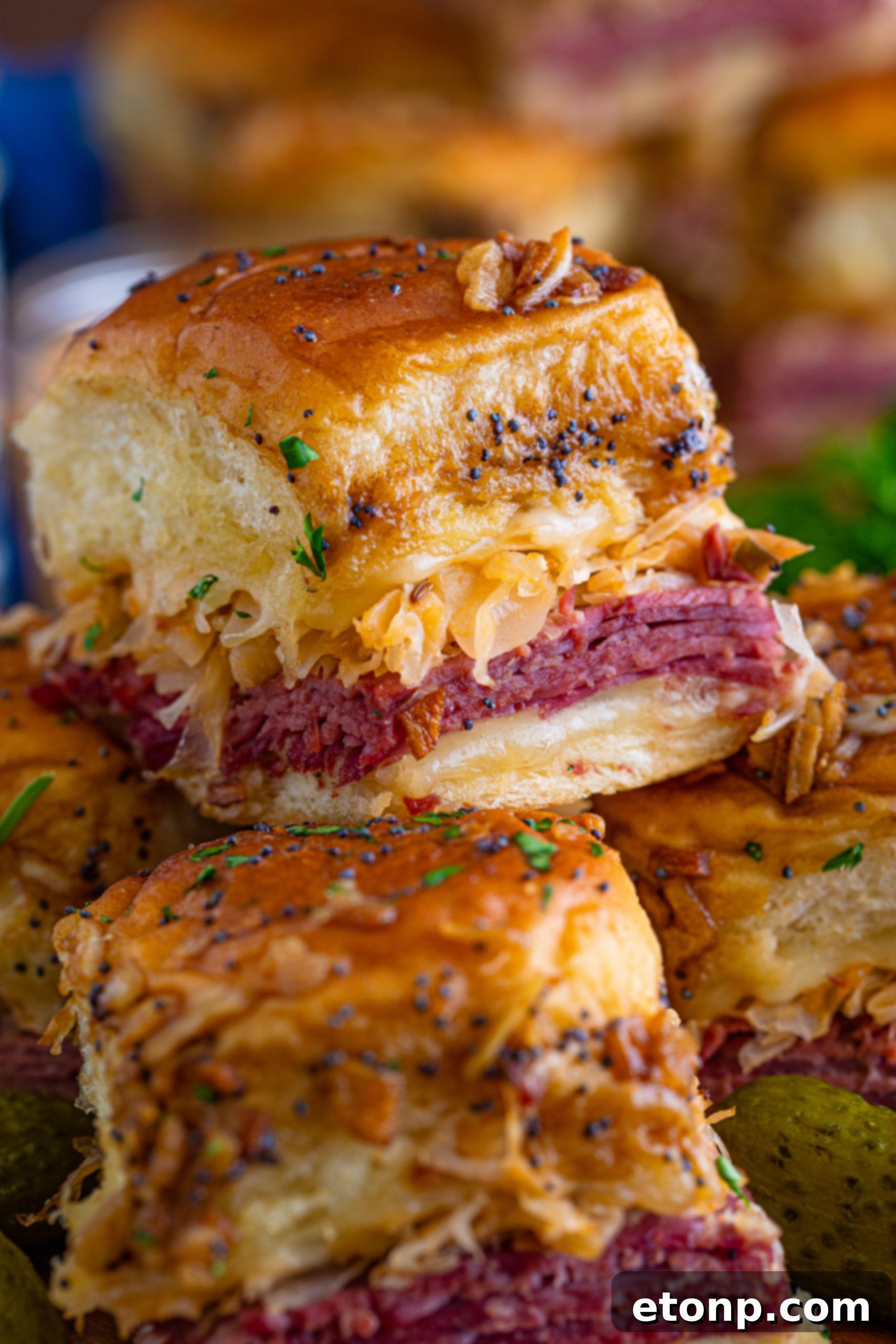 Mini Reuben Sandwiches 10 A person cutting baked Reuben Sliders into individual servings, highlighting their perfect golden crust and melted cheese.