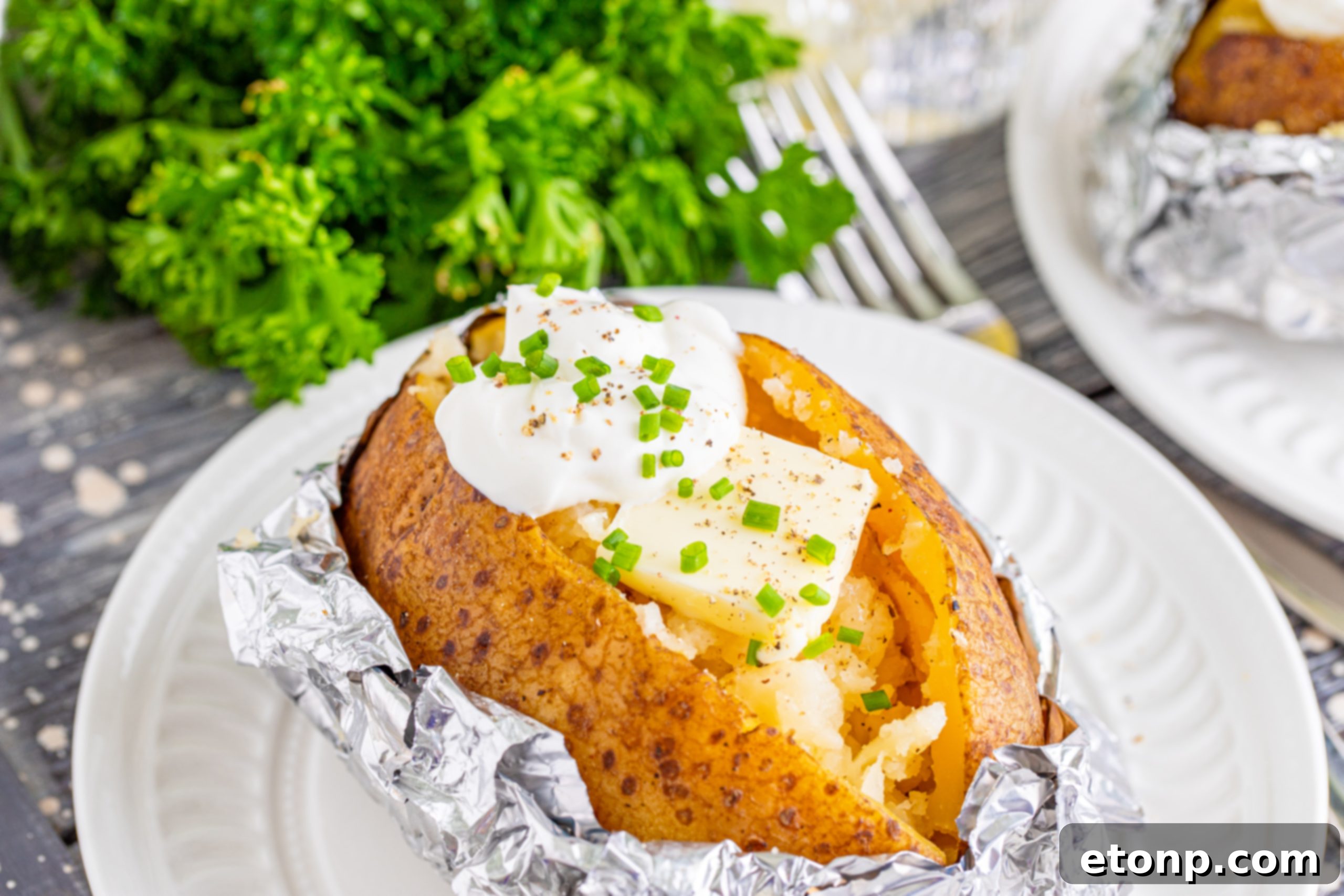 Two slow cooker baked potatoes topped with sour cream and chives