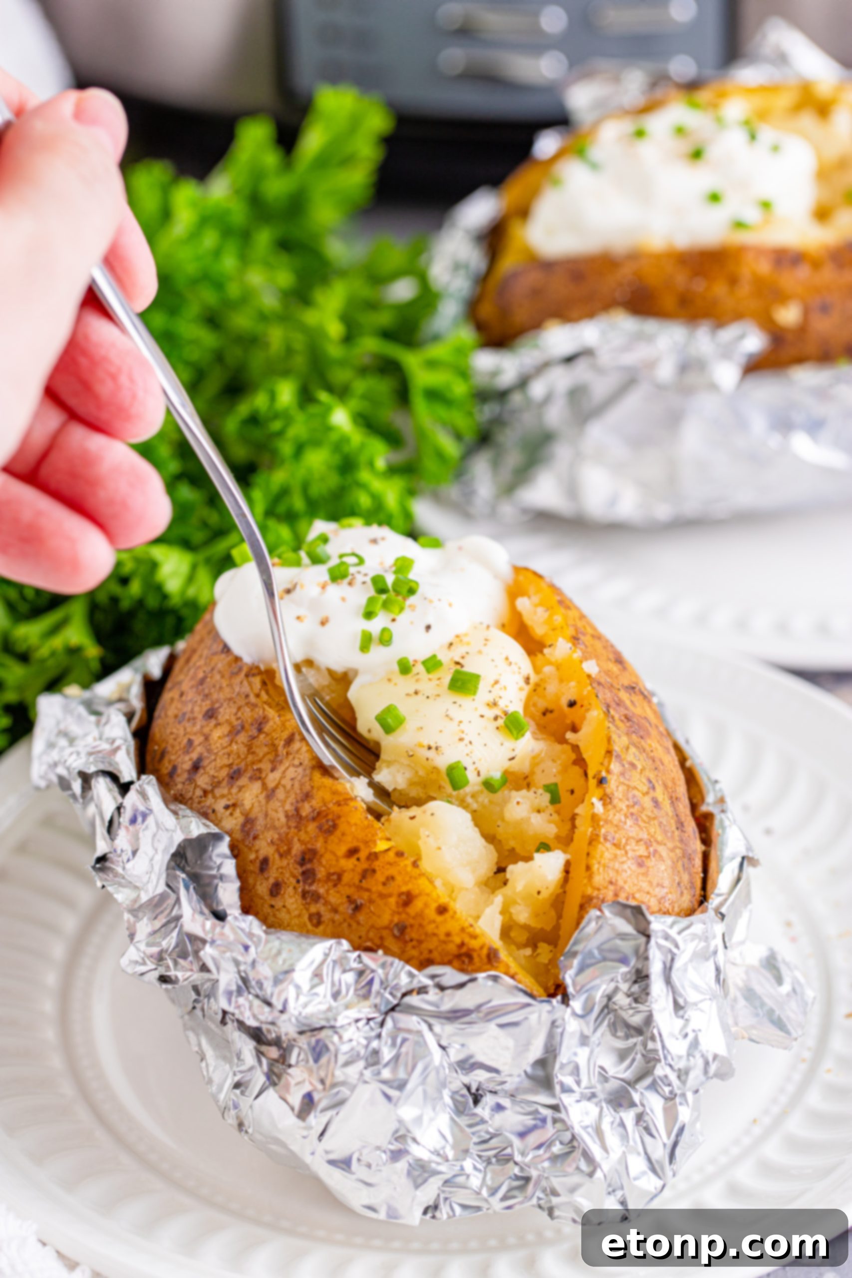 Two hands unwrapping a foil-baked potato