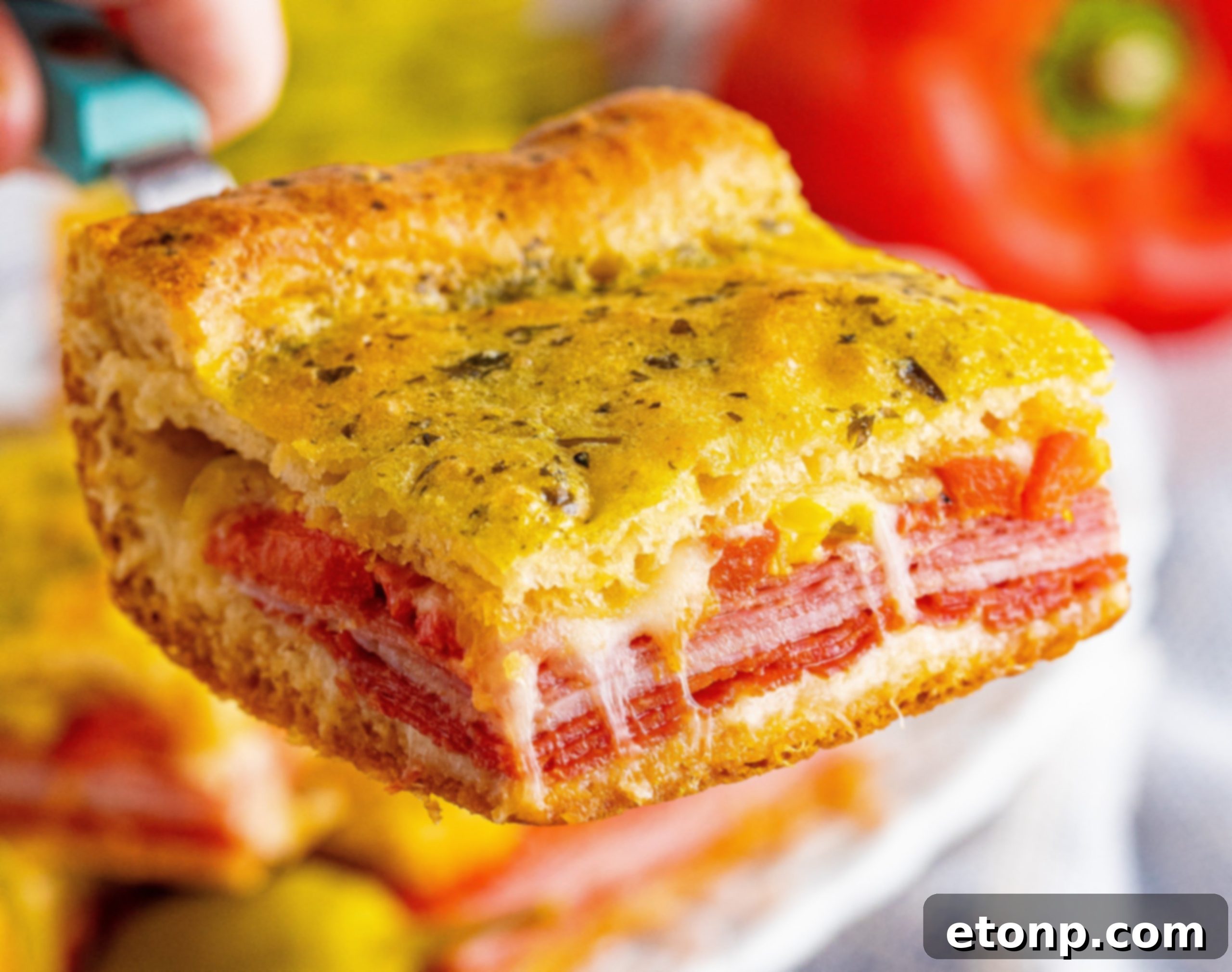 A baking dish filled with the layered ingredients of Antipasto Squares before the top crust is added, showing provolone cheese, deli meats, and peppers.
