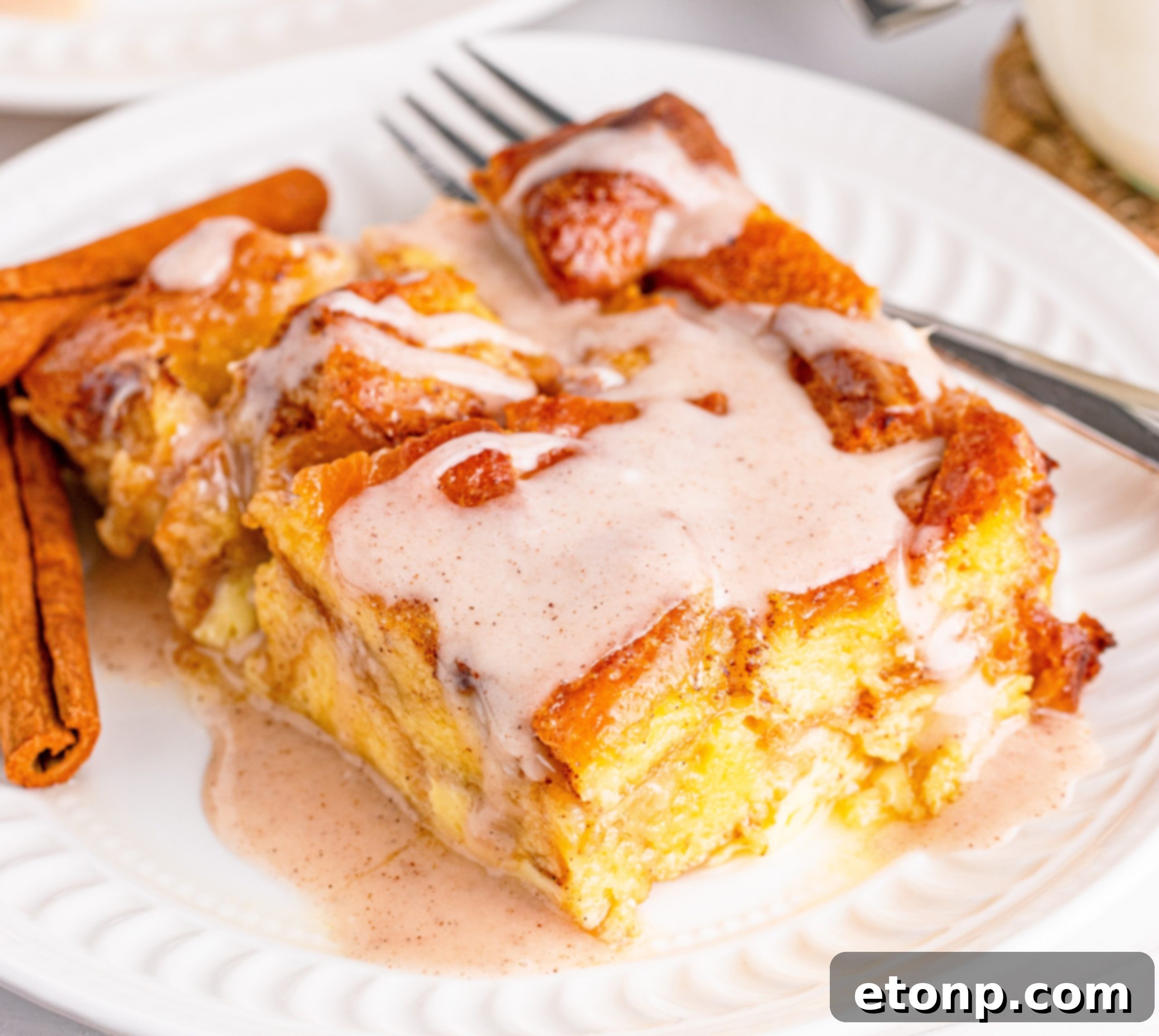 Glazed Honeybun Bread Pudding, warm and golden with cinnamon glaze dripping down