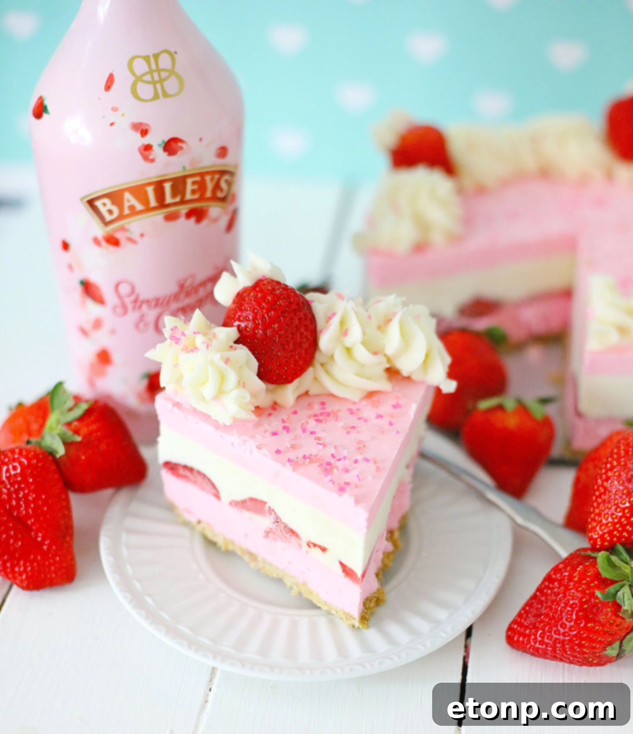 No-Bake Baileys Strawberry Cheesecake Bliss 2 Baileys Strawberries & Cream Cheesecake served on a plate with fresh strawberries