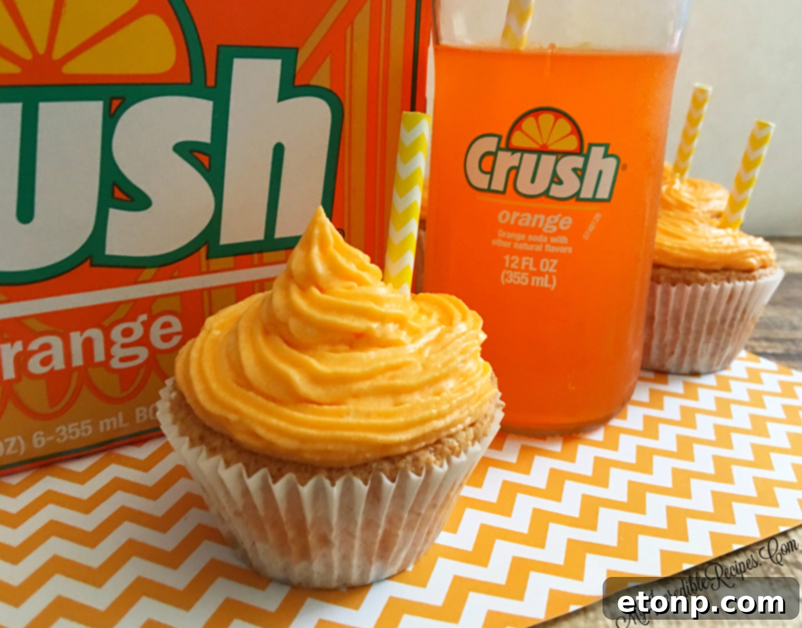Overhead view of multiple Orange Creamsicle Cupcakes, garnished with colorful paper straws, inviting a taste