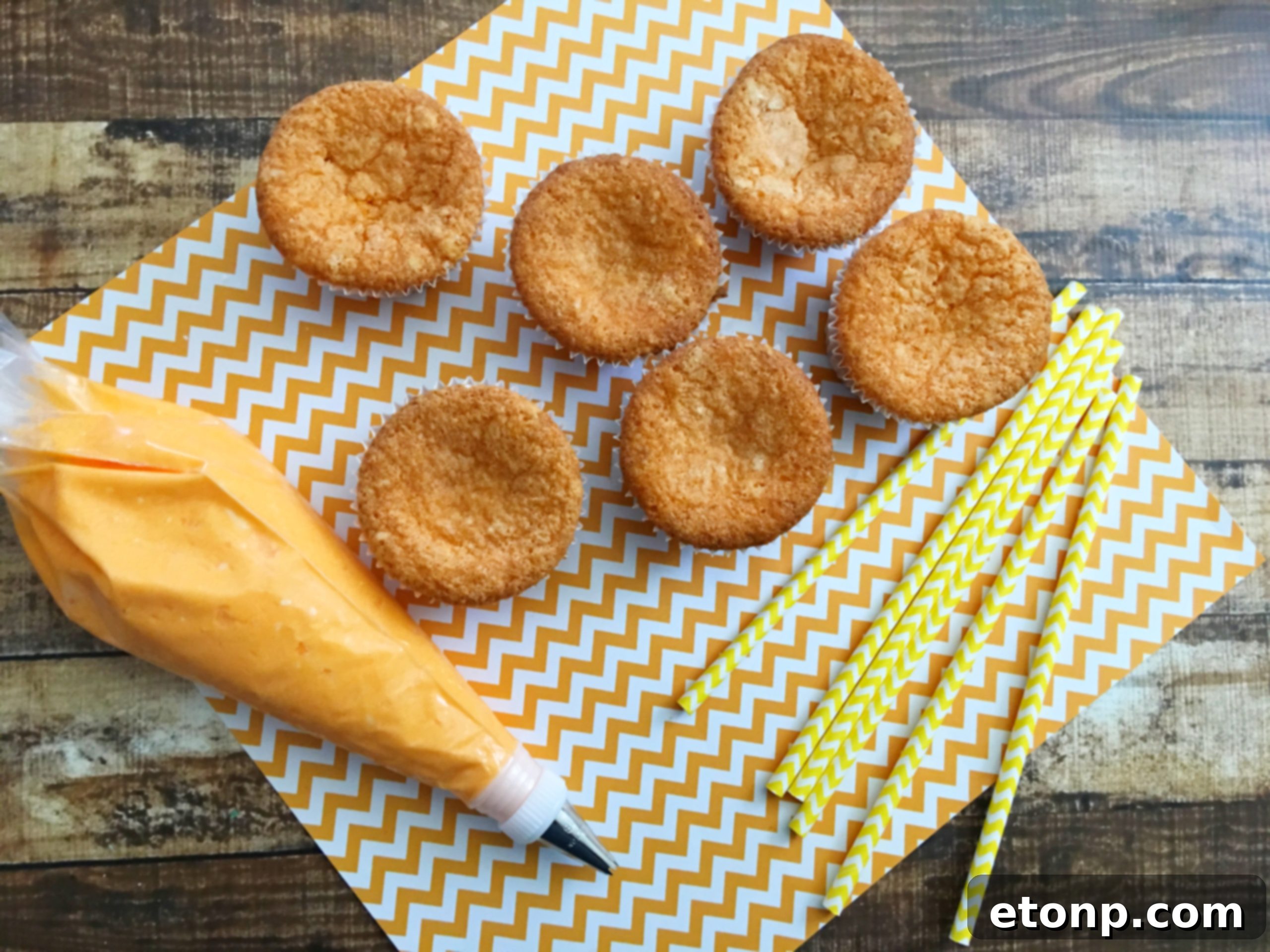 A single Orange Creamsicle Cupcake, perfectly frosted and ready to be eaten, with a playful paper straw