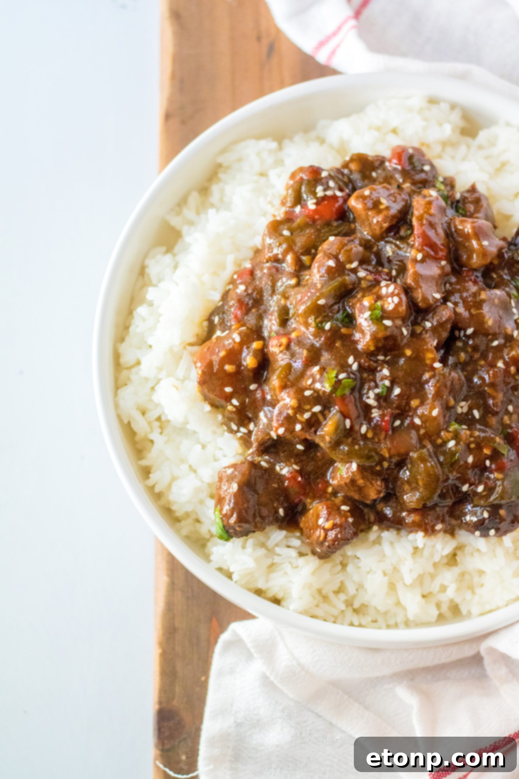 Slow Cooker Pepper Steak served on a plate with white rice, garnished with fresh cilantro.