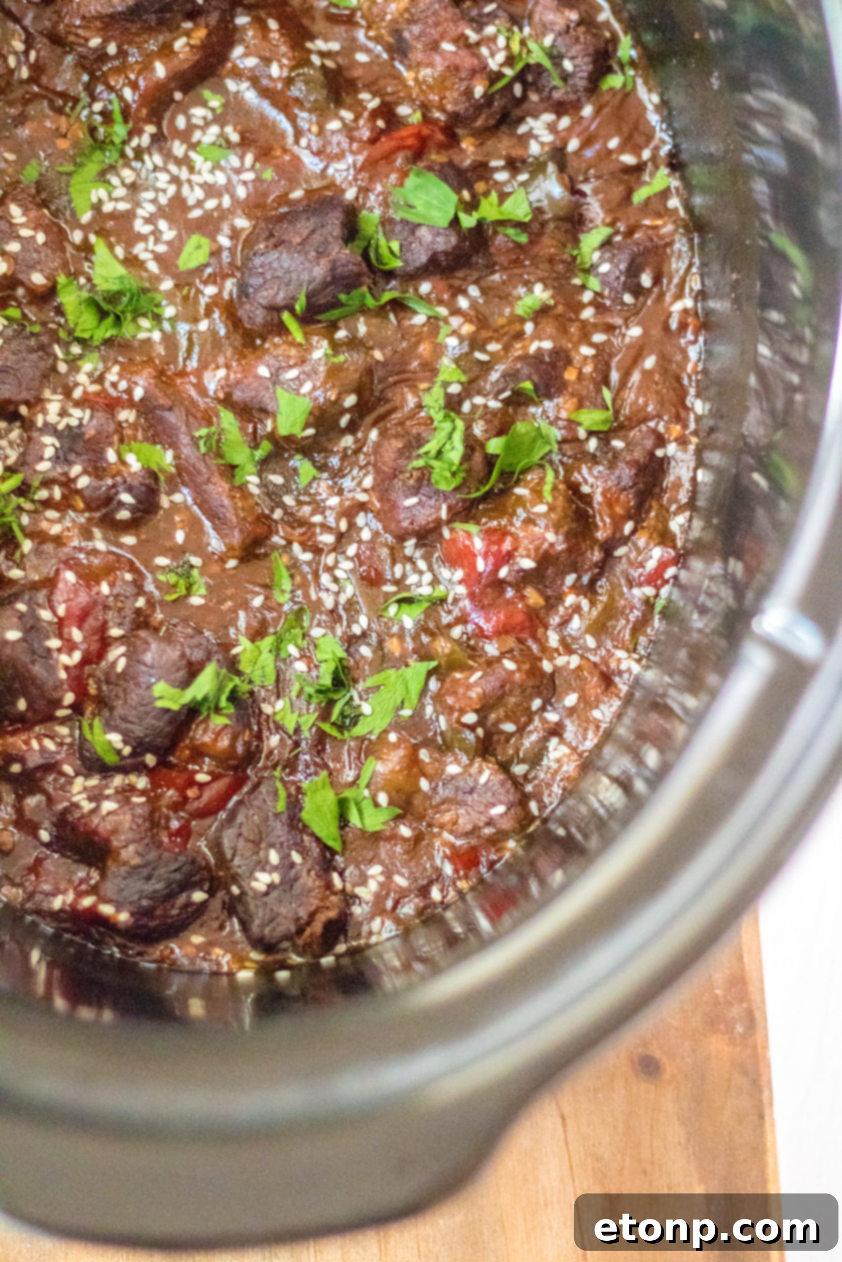 Slow Cooker Pepper Steak with a spoon scooping a portion, showing the tender beef and gravy.