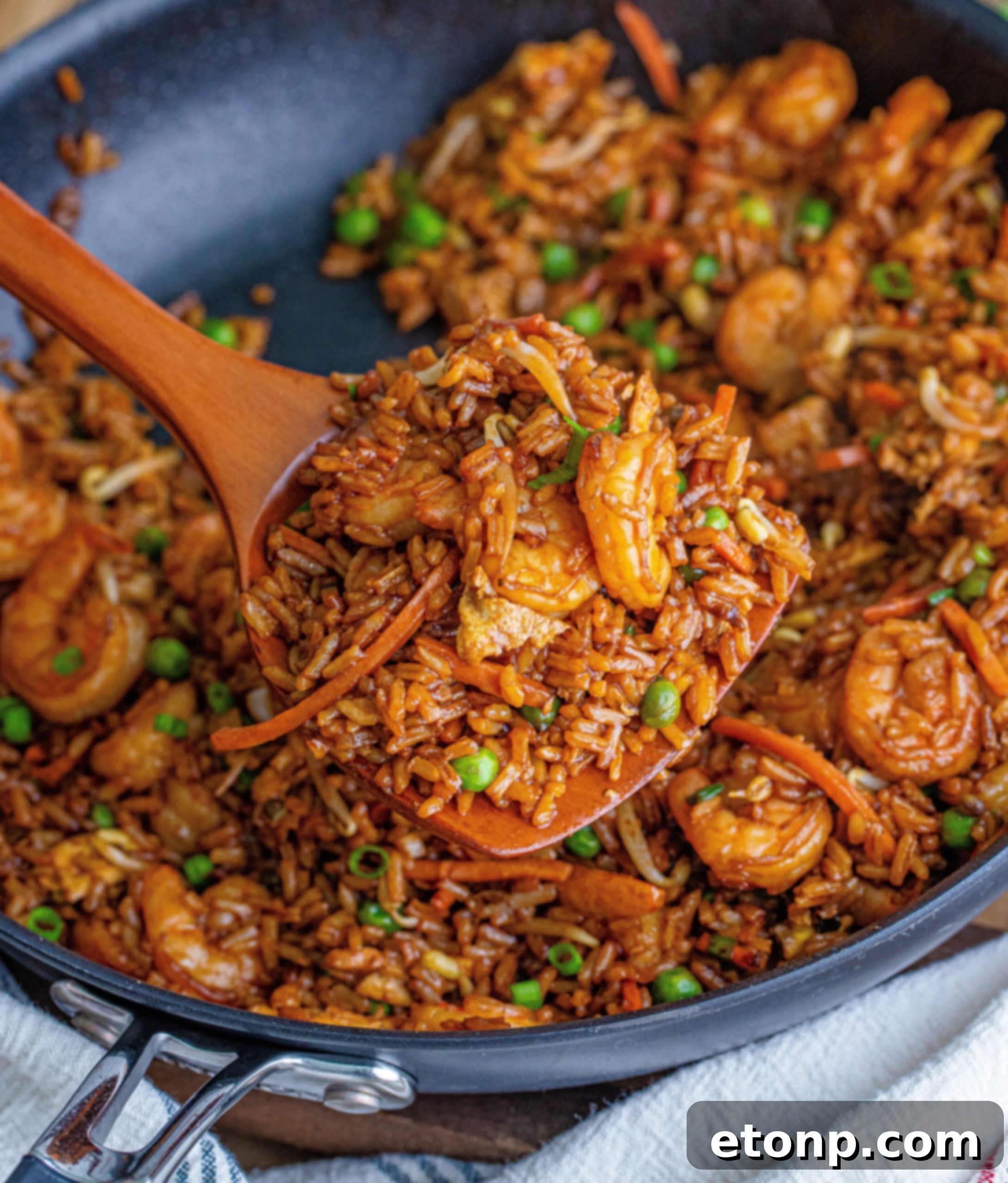 Golden Shrimp Fried Rice 4 A large skillet filled with shrimp, vegetables, and rice being stir-fried.