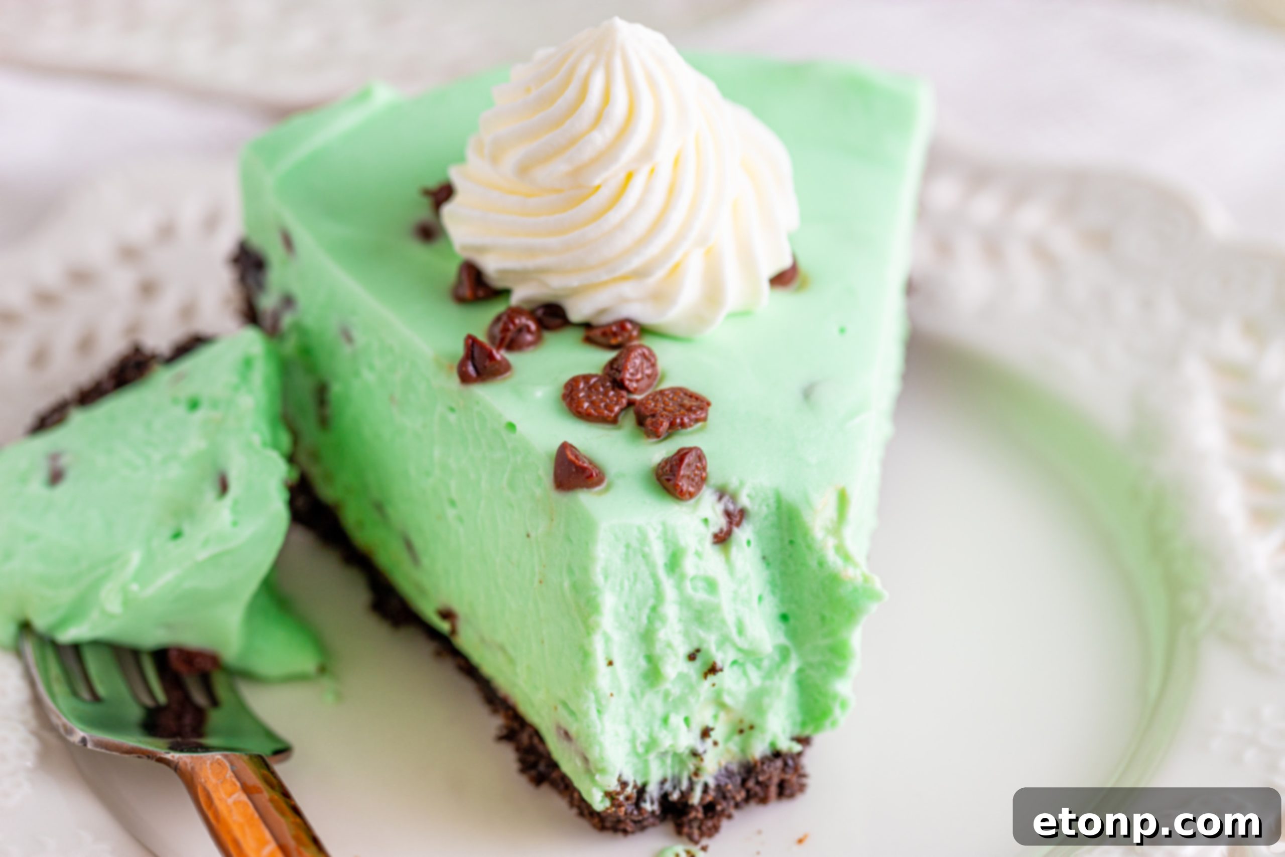 Two slices of vibrant green mint chocolate chip cheesecake served on plates, ready to be enjoyed