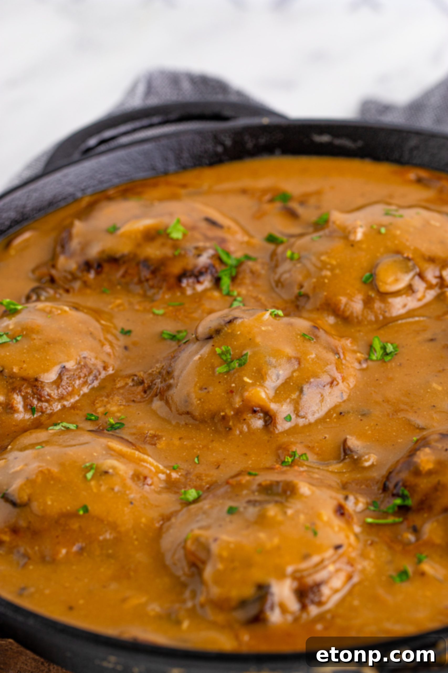 Salisbury Steak patties cooking in a cast iron skillet