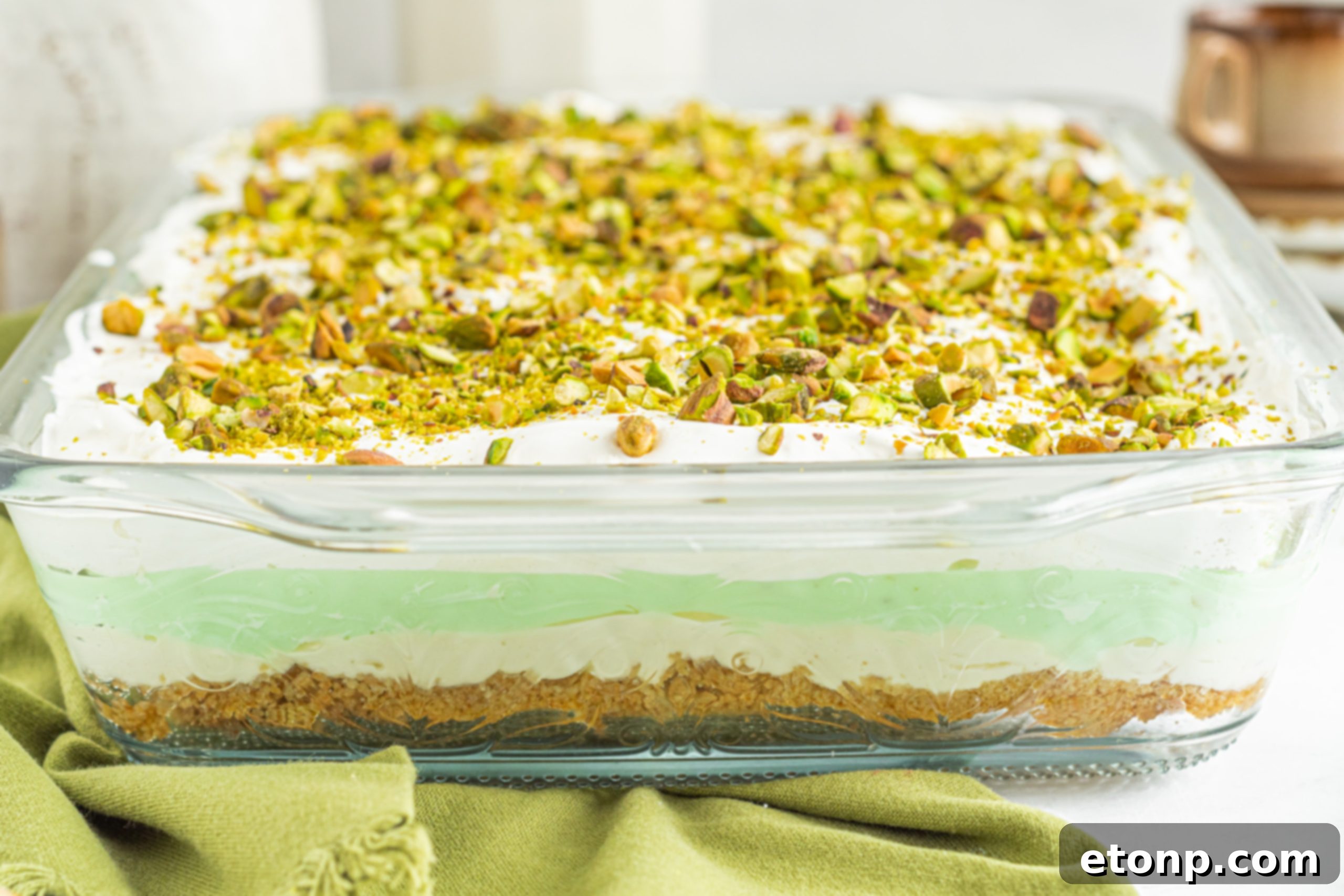 Pistachio Lush Dessert presented beautifully on a marble surface, with serving utensils nearby, hinting at its readiness.