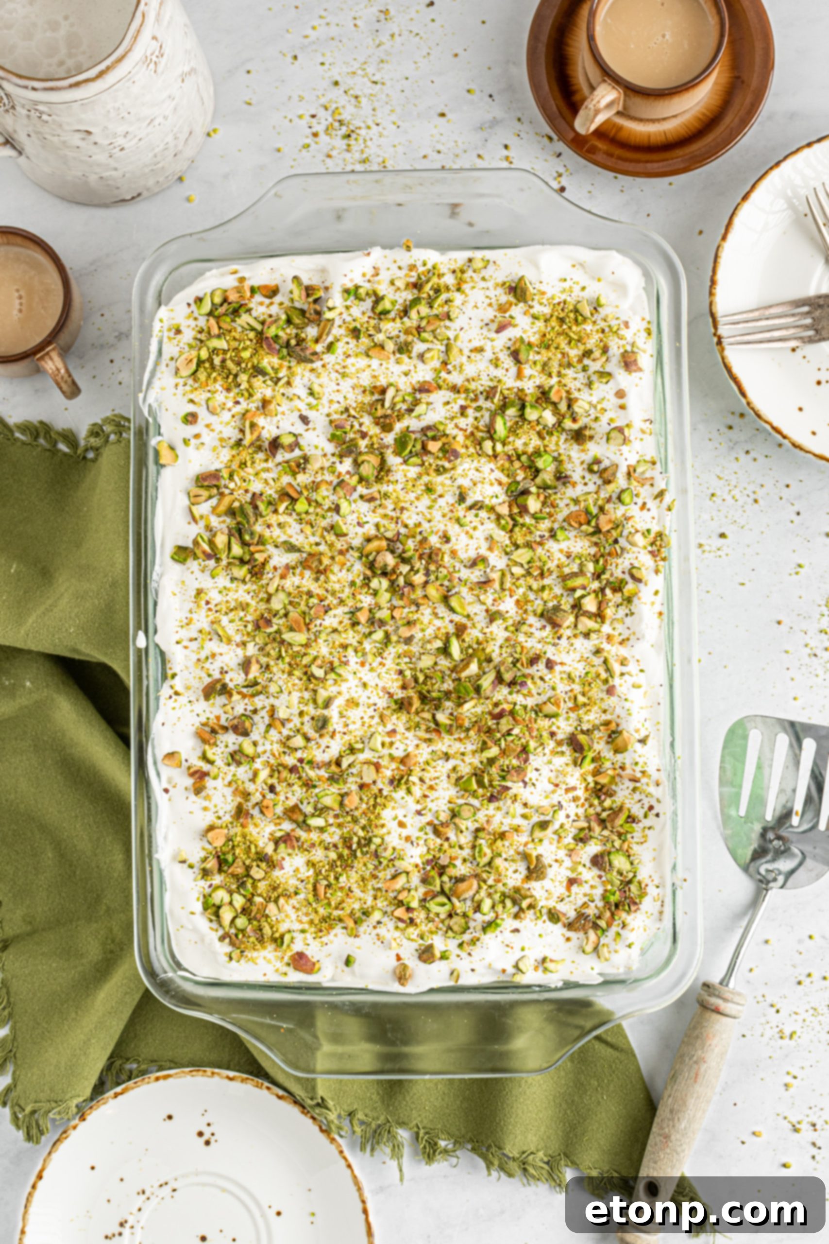 Overhead shot of an entire Pistachio Lush Dessert in a glass baking dish, beautifully layered and topped with whipped cream and crushed pistachios.