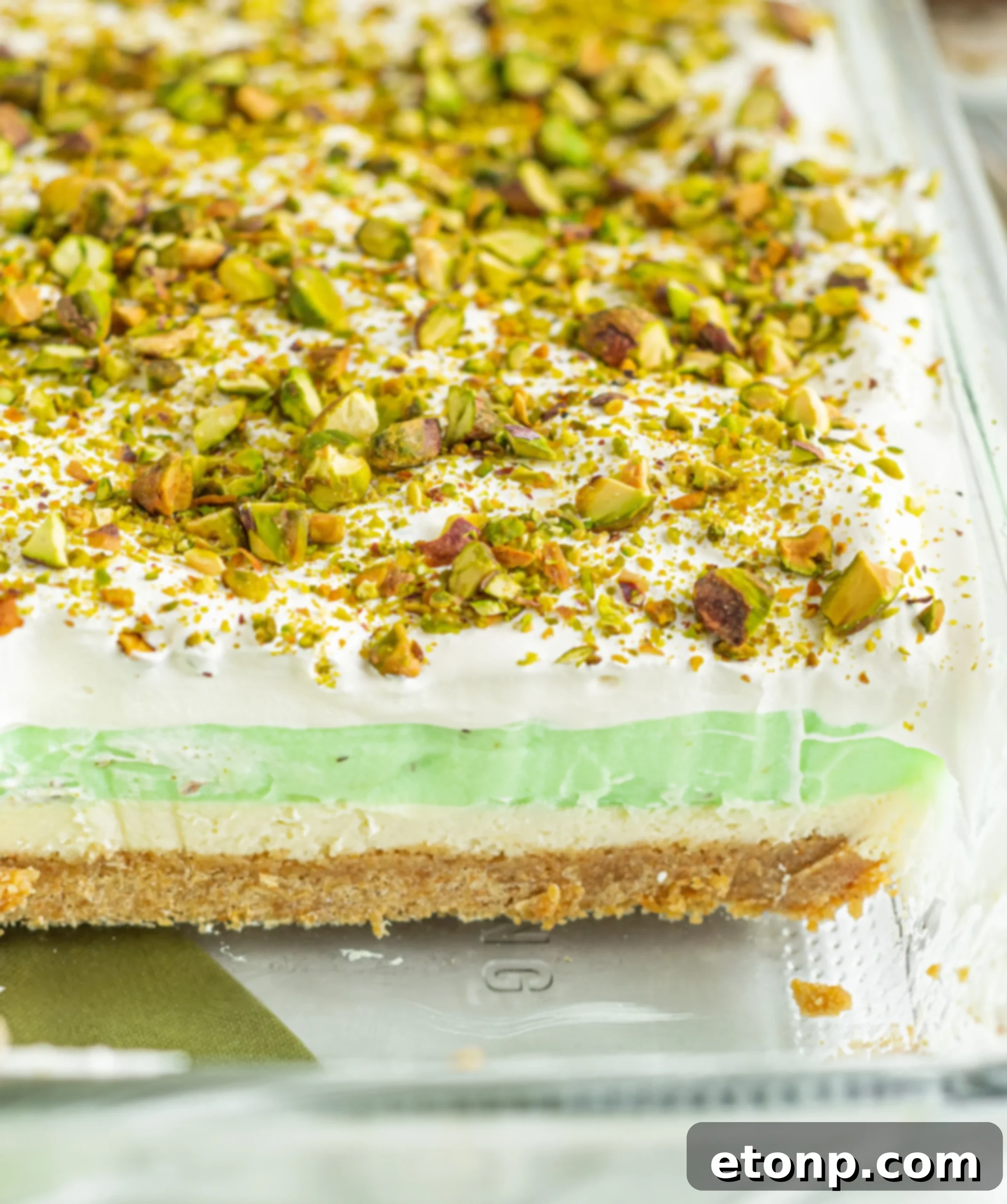 A serving of Pistachio Lush Dessert on a white plate, with a spoon taking a scoop, highlighting the creamy texture.