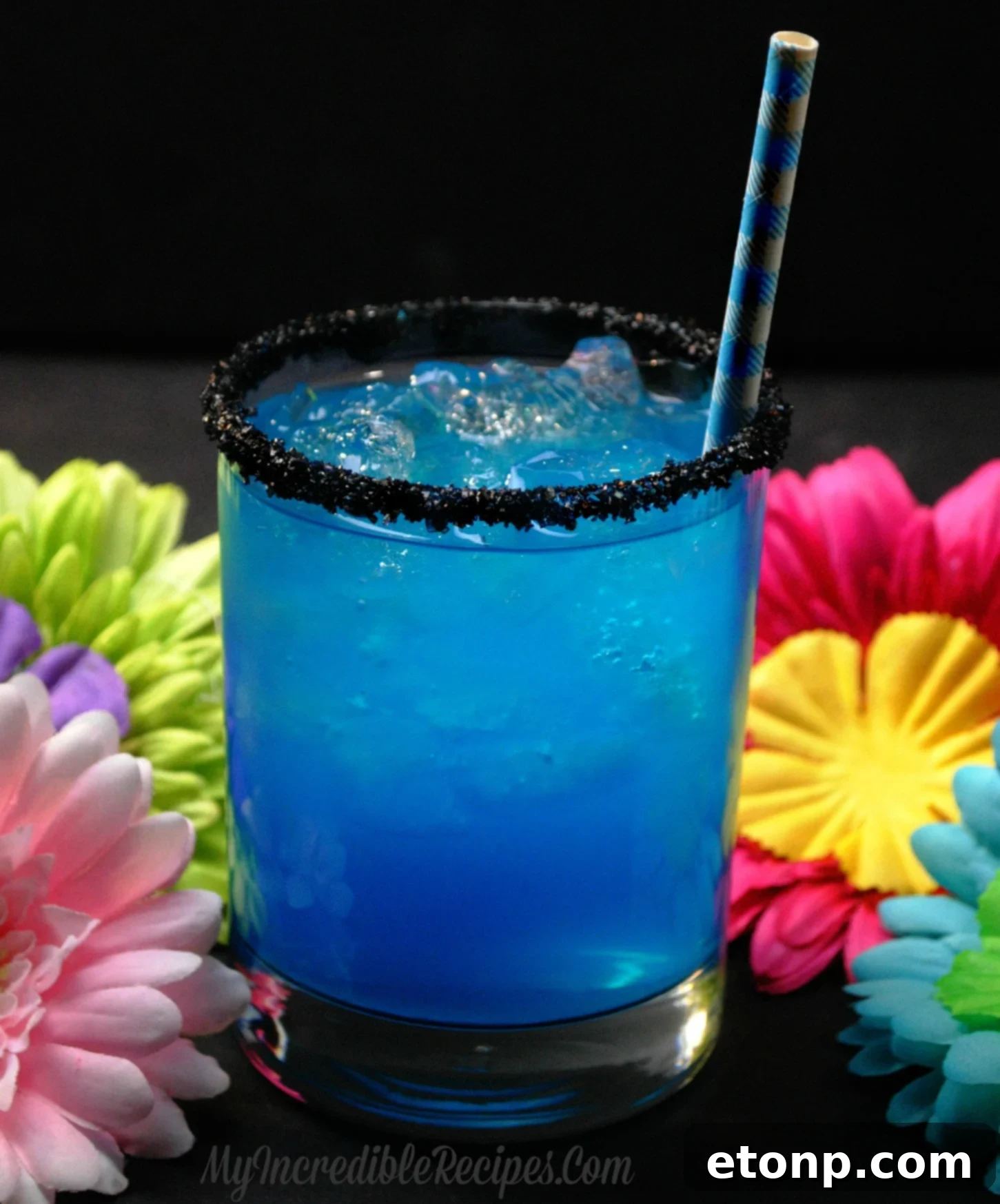 A visually stunning Hookah Butterfly Cocktail in an elegant glass, garnished with a black sugared rim, showcasing its vibrant blue, purple, and pink layered hues.