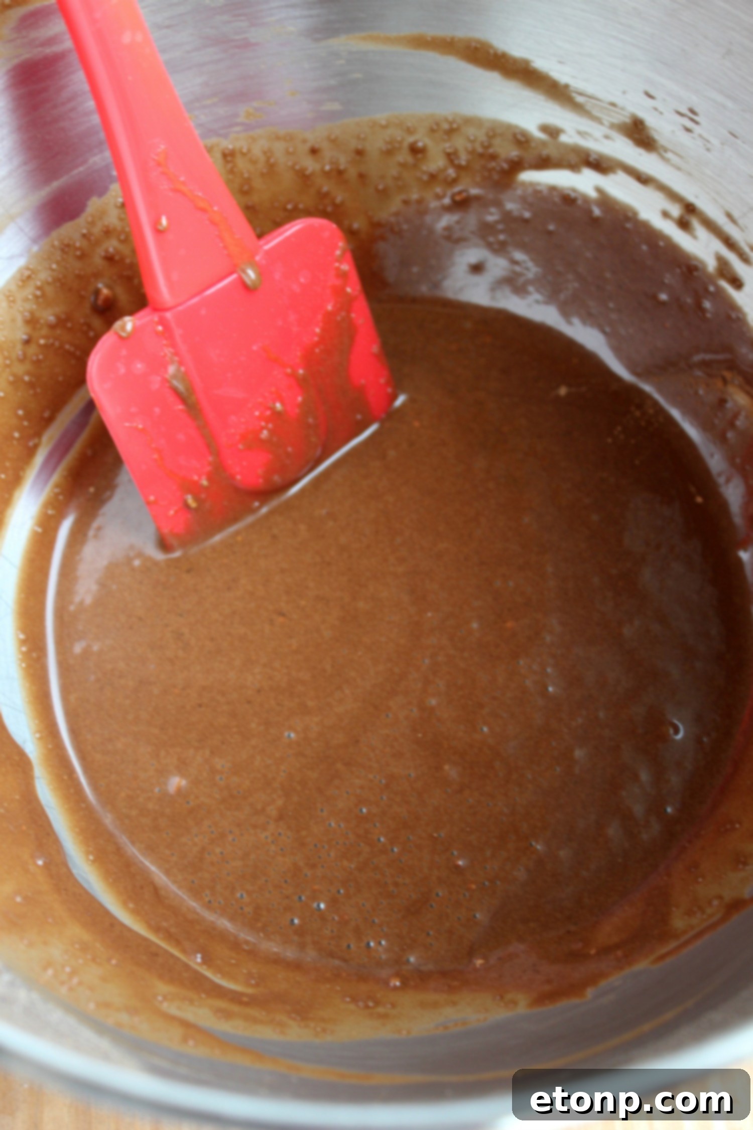 Close-up shot of rich chocolate cupcake batter being mixed in a bowl, showcasing the perfect consistency.