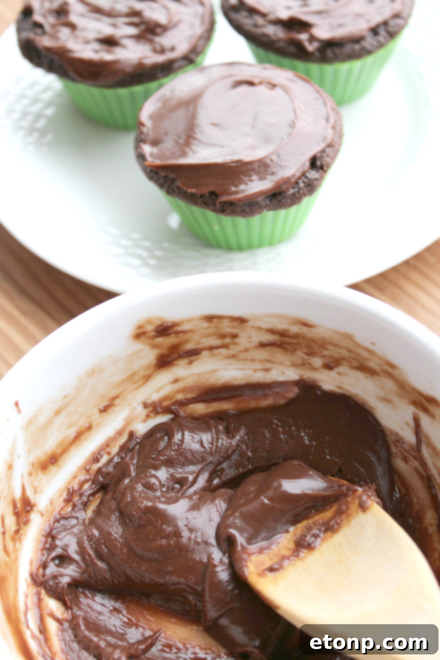 Delicious chocolate cupcakes being carefully dipped into a rich, glossy chocolate ganache.