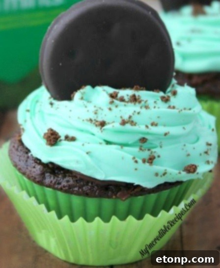A single Thin Mint cupcake, beautifully frosted in green, topped with a whole Thin Mint cookie.