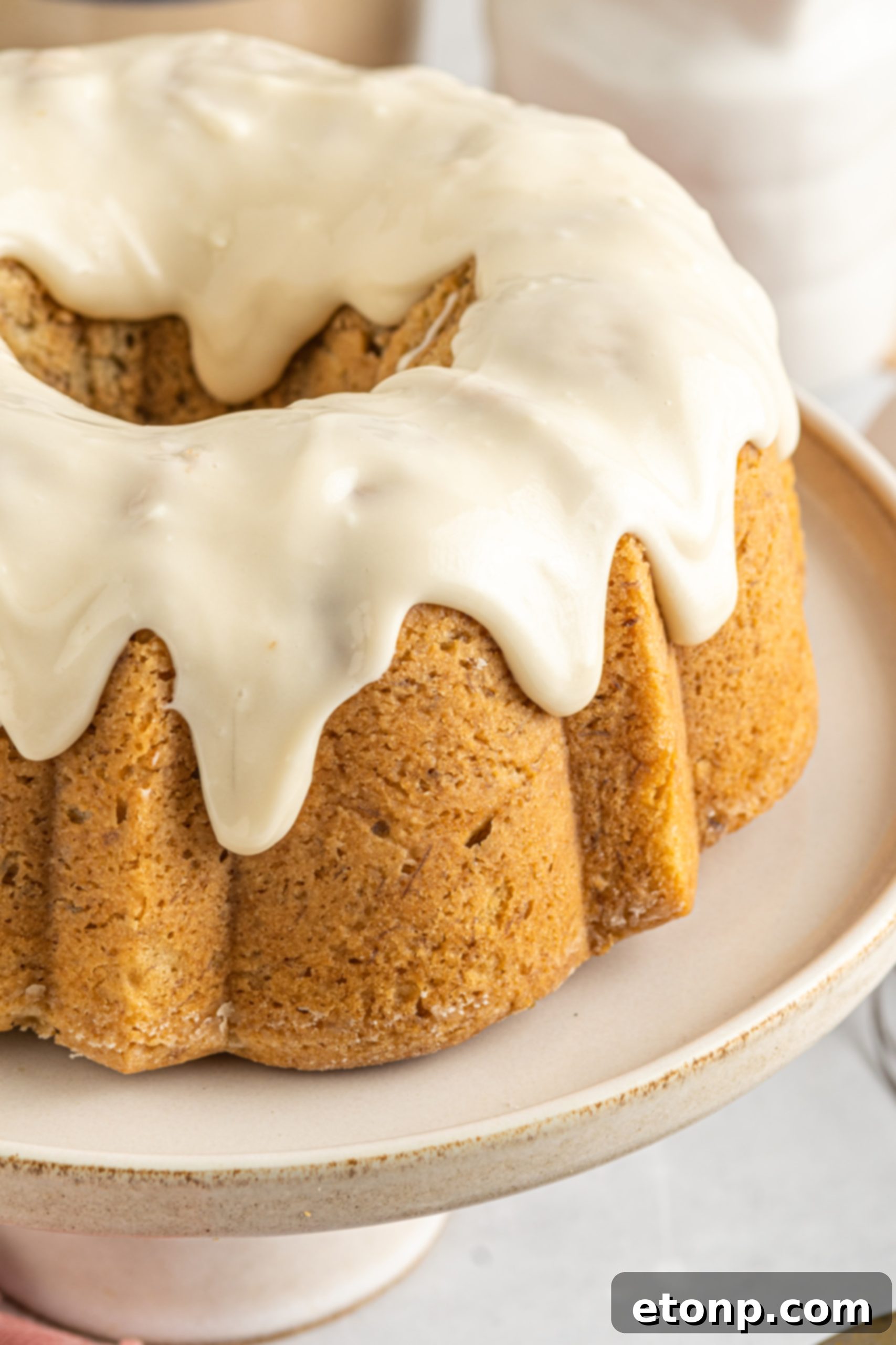 Banana Cake covered in sour cream frosting on a cake stand