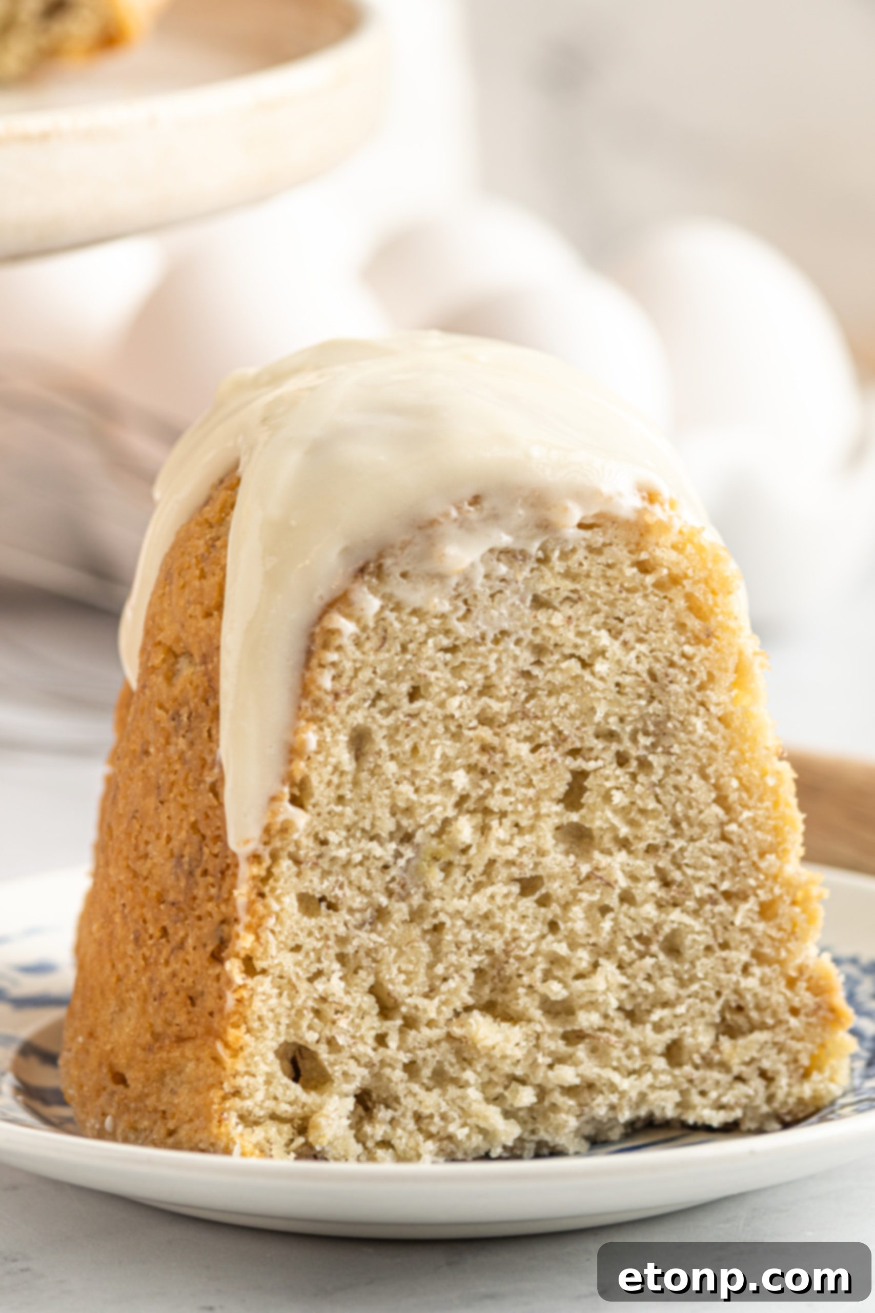 Banana Cake covered in sour cream frosting cake slice on a plate