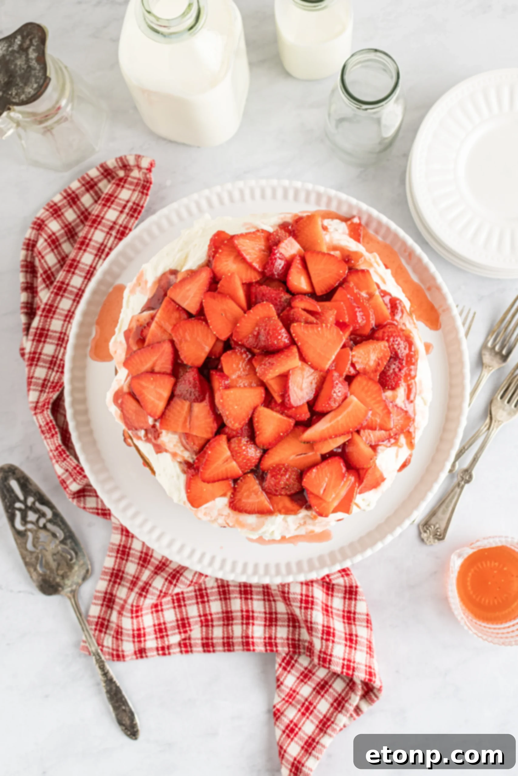 Beautifully decorated Strawberry Whipped Cream Cake with whole and sliced strawberries on top.