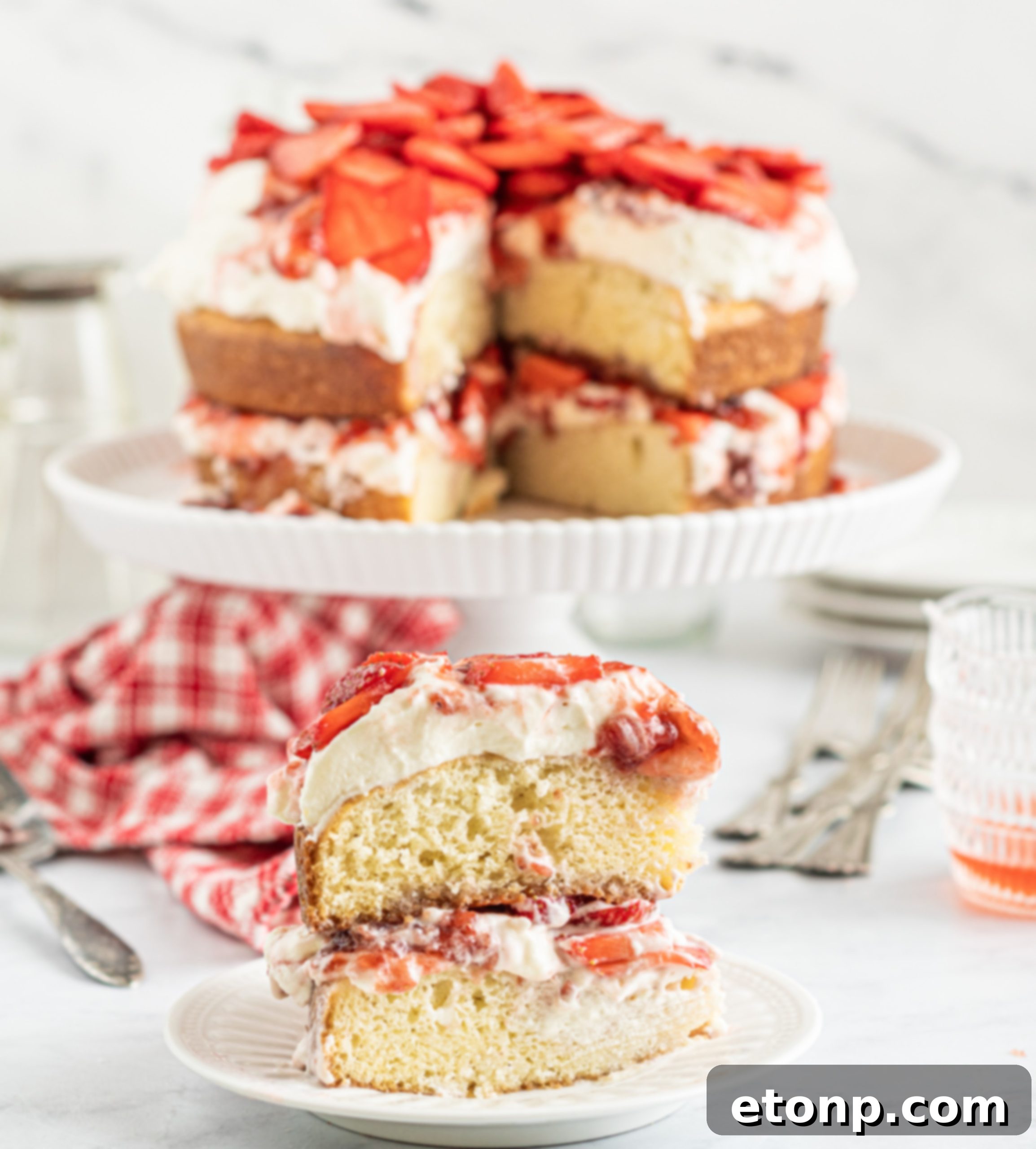 A large slice of Strawberry Whipped Cream Cake on a white plate, highlighting the layers.