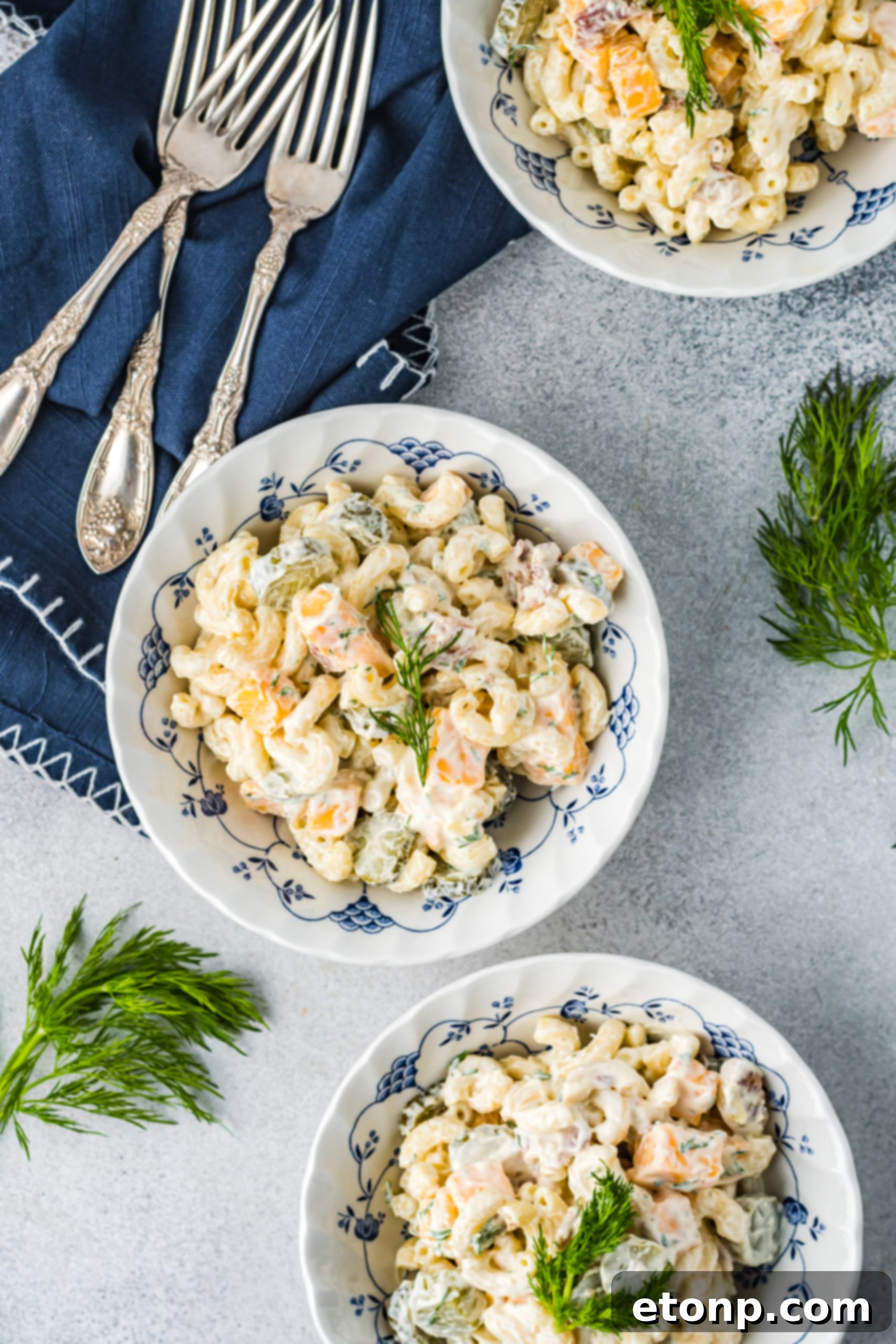 A large bowl of Dill Pickle Pasta Salad on a rustic wooden table, ready to be served at a gathering.