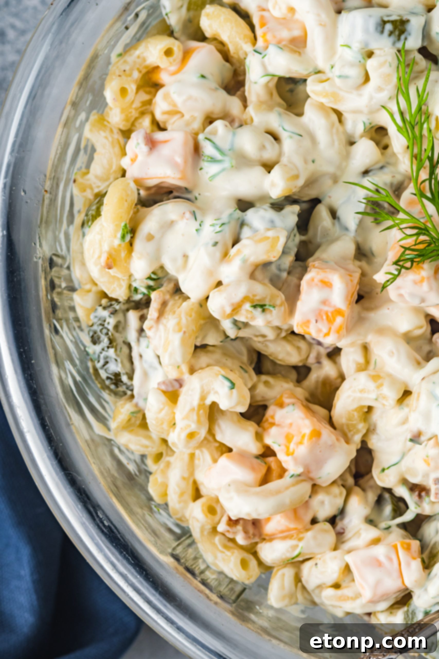 Close-up of a bowl of Dill Pickle Pasta Salad with a fork, showing the texture of the pasta, pickles, and dressing.