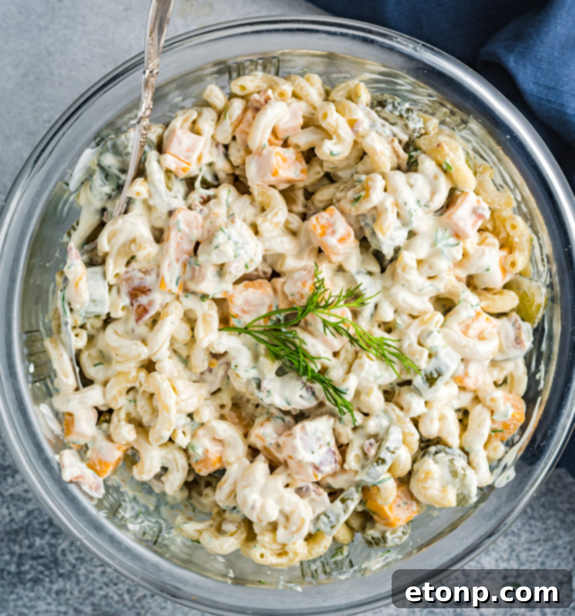 A serving of Dill Pickle Pasta Salad in a glass bowl, focusing on the fresh dill garnish.
