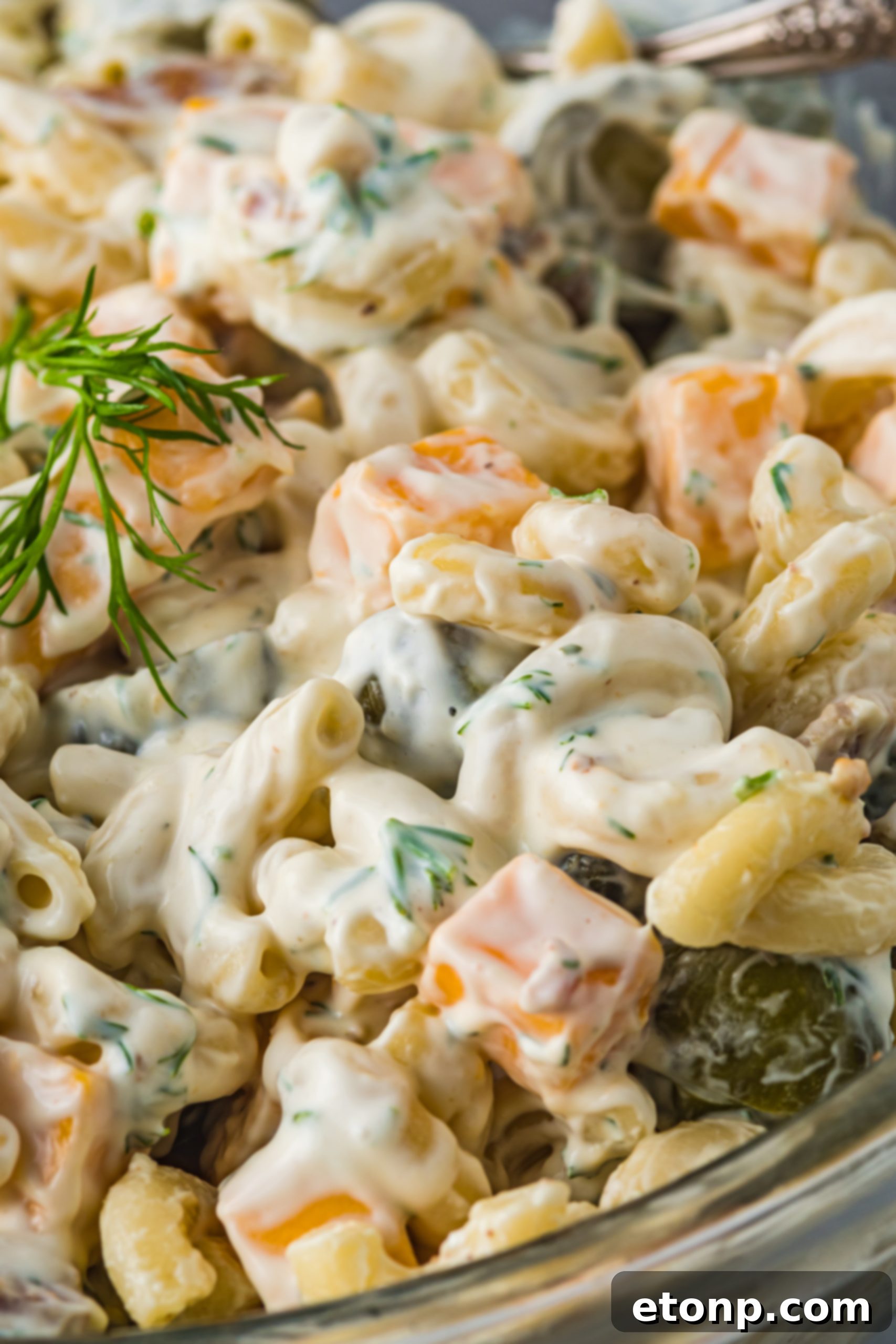 A spoonful of Dill Pickle Pasta Salad being scooped from a bowl, highlighting its creamy texture.