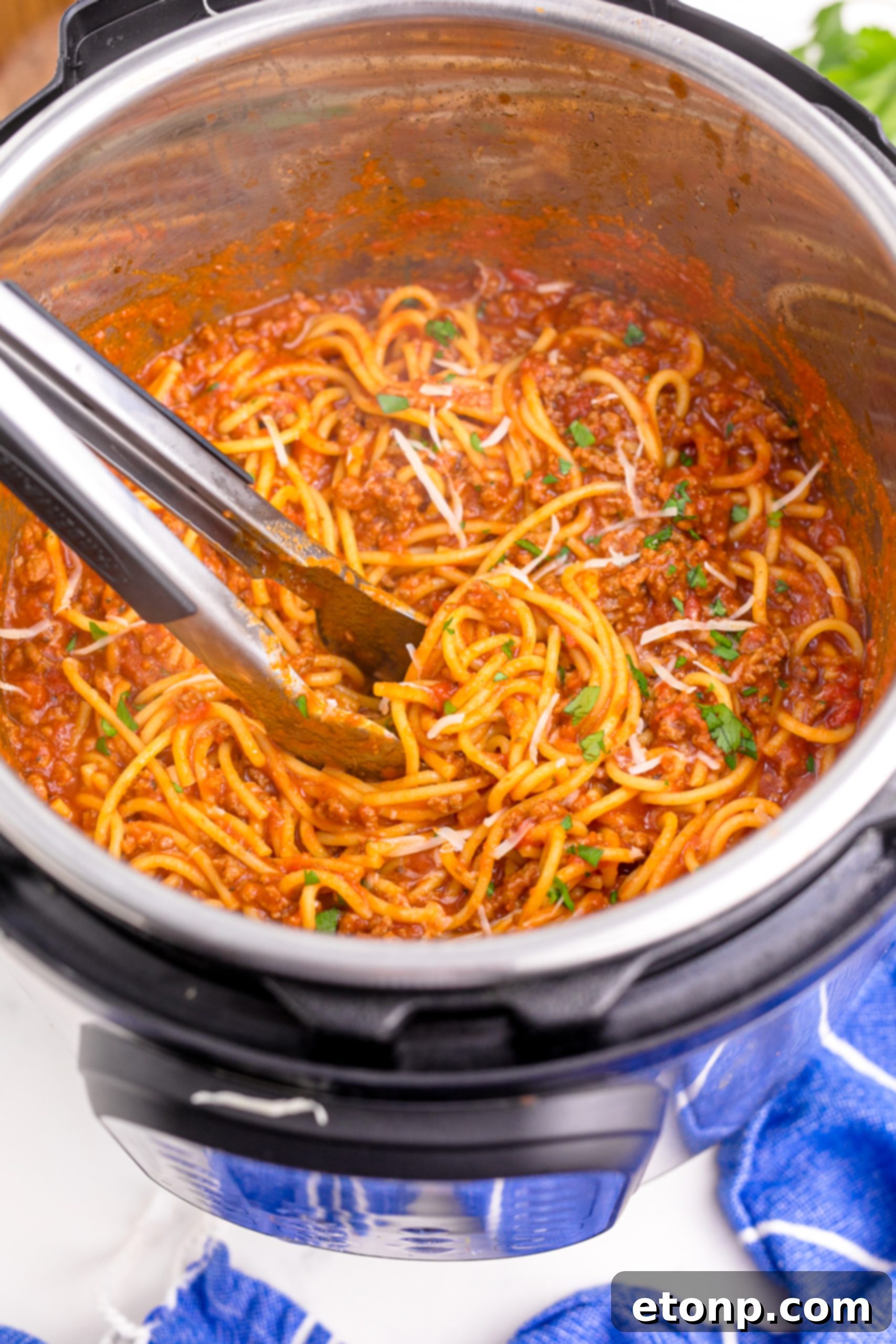 One-Pot Instant Pot Spaghetti 13 Instant Pot Spaghetti being mixed with tongs in the Instant Pot, sprinkled with Parmesan cheese and parsley