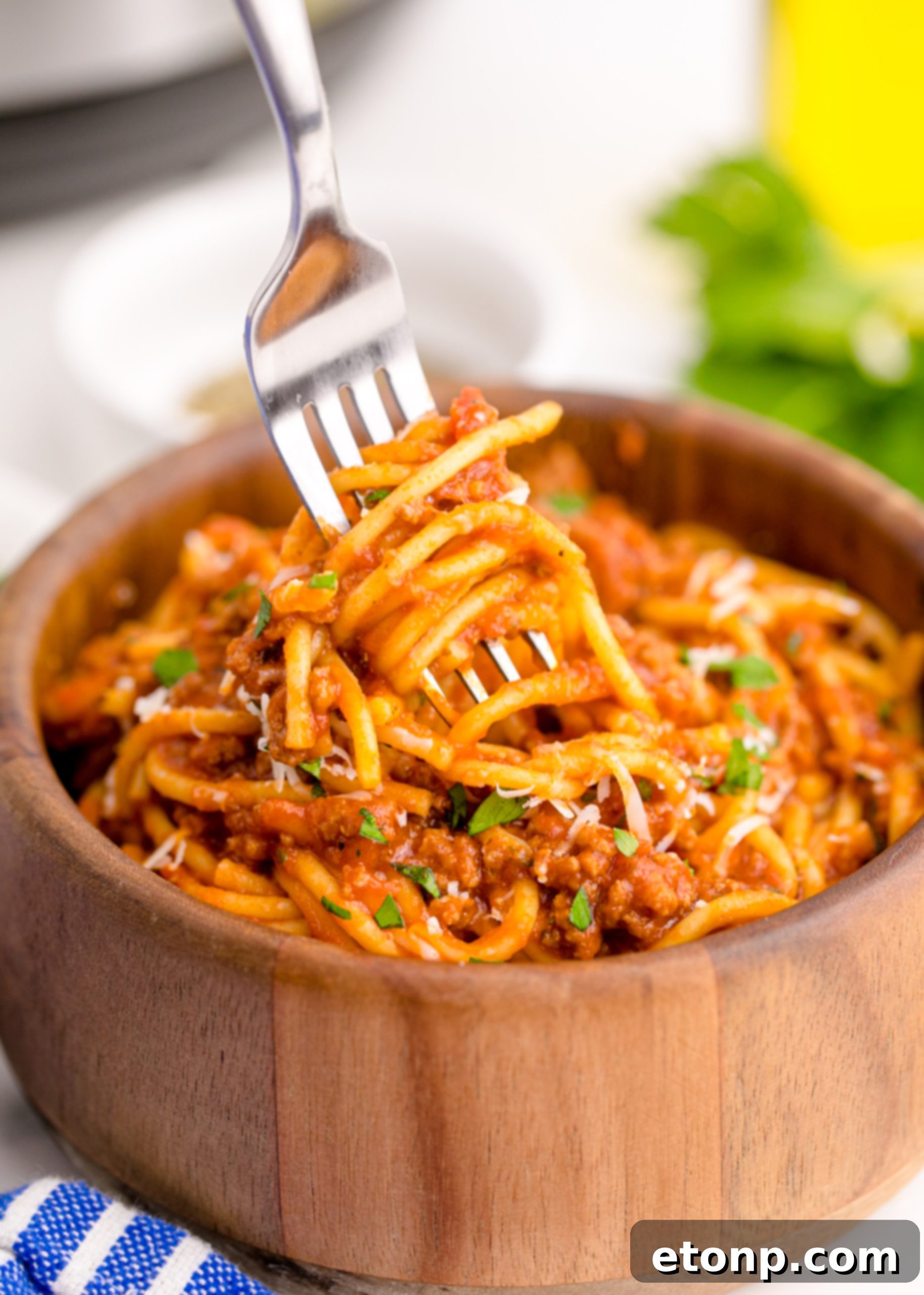One-Pot Instant Pot Spaghetti 16 Instant Pot Spaghetti in a wooden bowl with a fork lifting some spaghetti