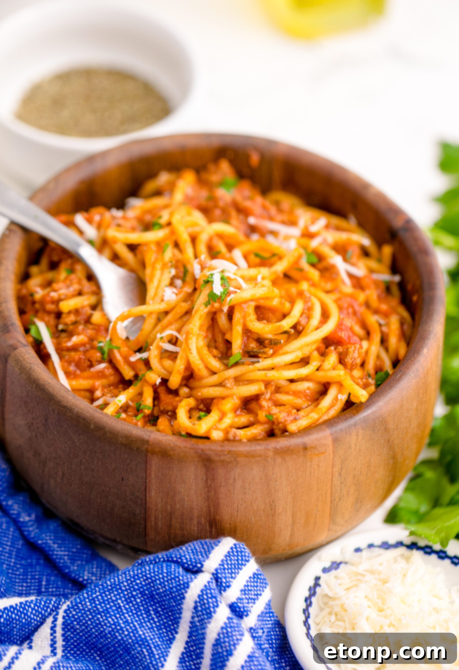 One-Pot Instant Pot Spaghetti 7 Instant Pot Spaghetti in a wooden bowl with a fork lifting the spaghetti up, showing its texture and sauce