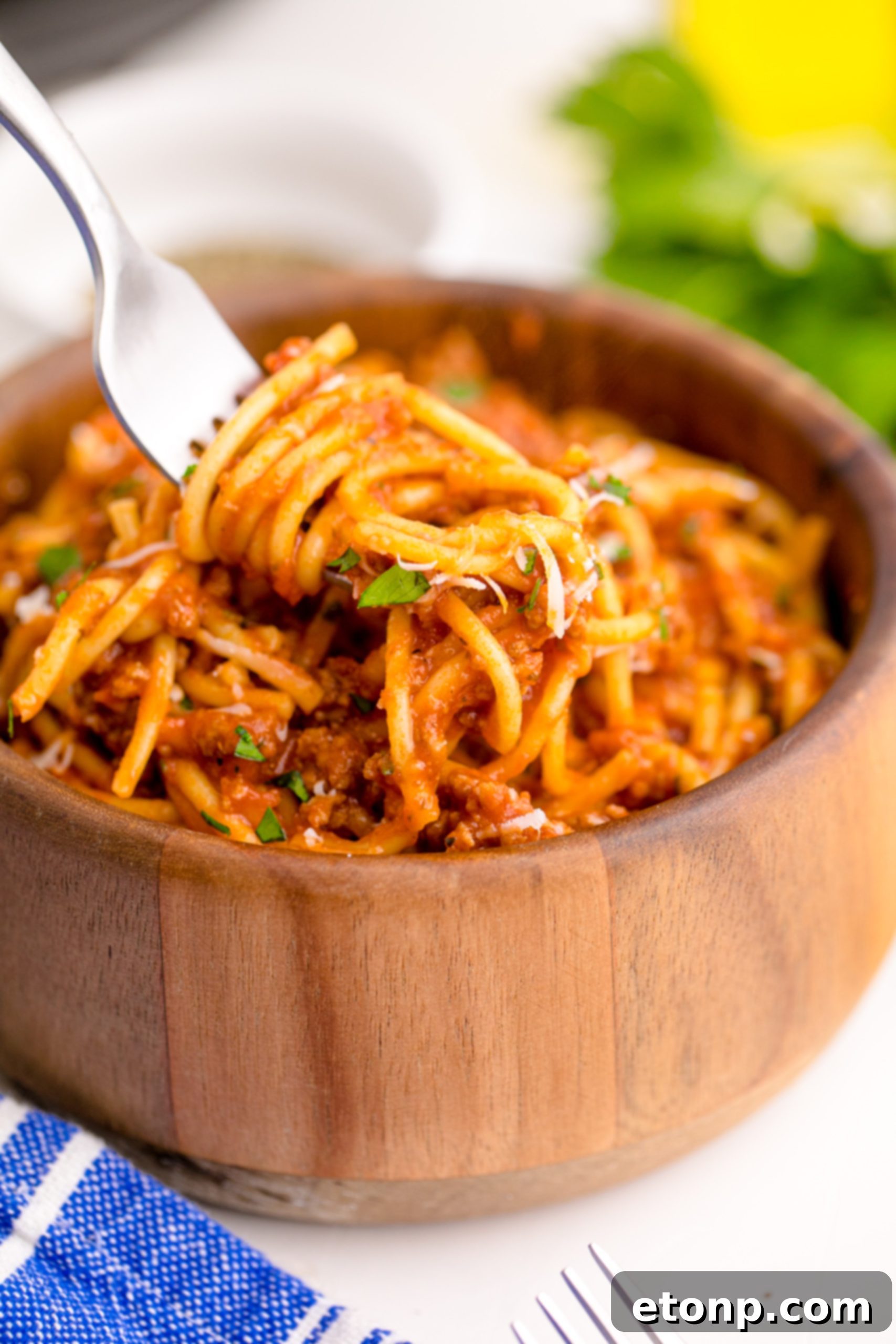 One-Pot Instant Pot Spaghetti 8 A close-up of Instant Pot Spaghetti in a wooden bowl, with a fork lifting some spaghetti