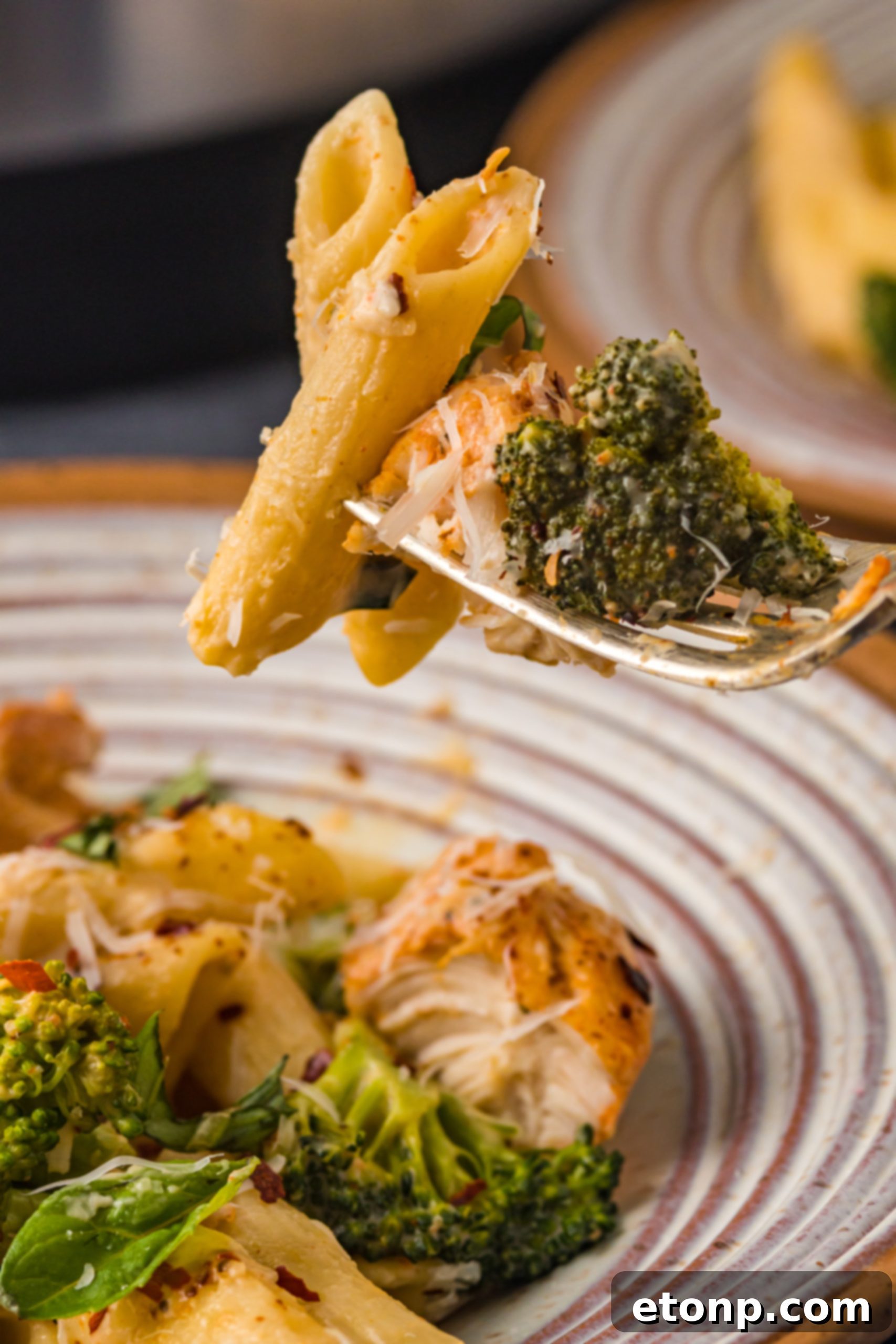 Chicken Pasta Delight 11 A fork lifting a generous portion of creamy chicken pasta, showcasing the melted cheese and tender chicken.