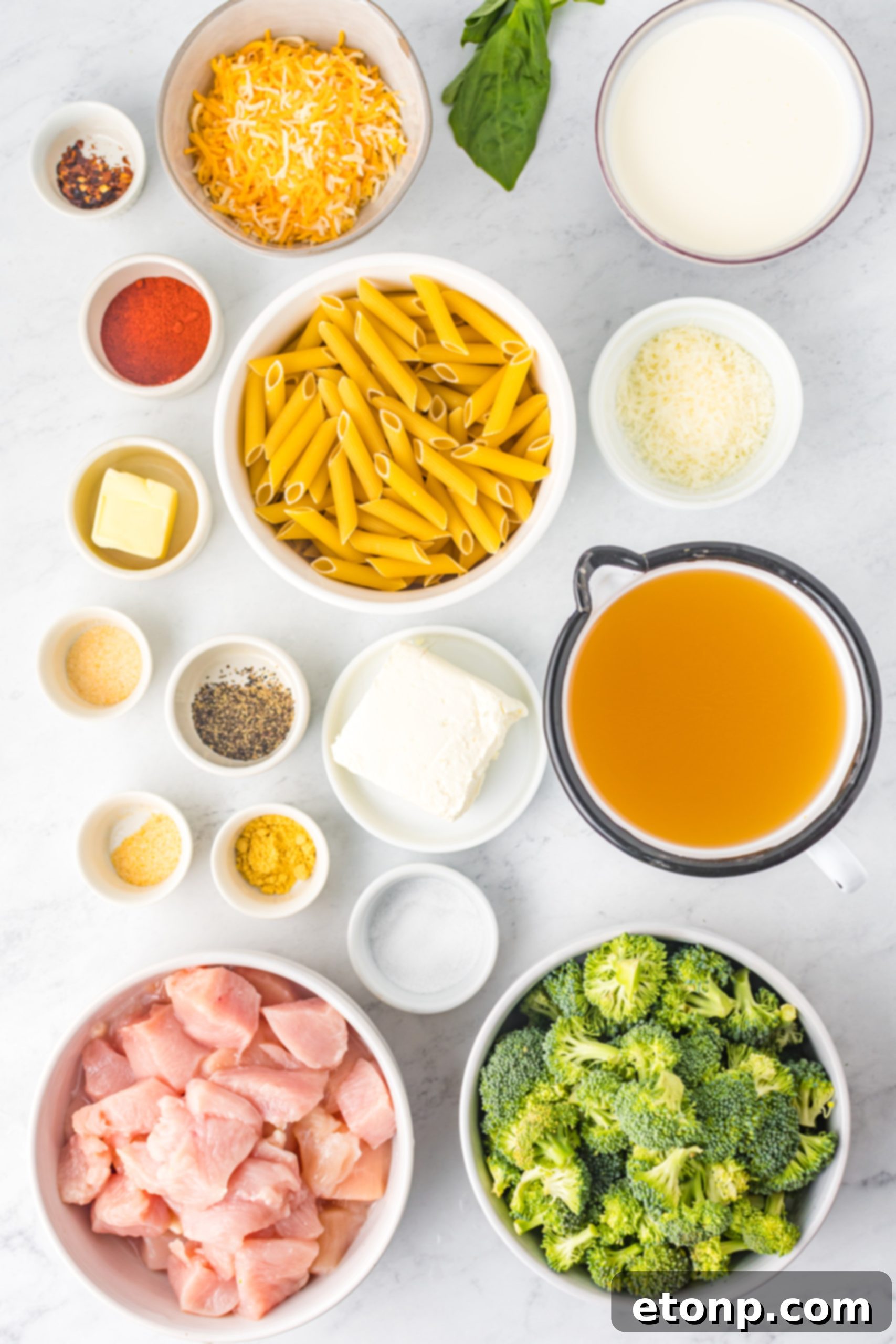Chicken Pasta Delight 3 A flat lay image displaying all the fresh ingredients needed for creamy chicken pasta, including diced chicken breast, penne pasta, various cheeses, heavy cream, and seasonings.