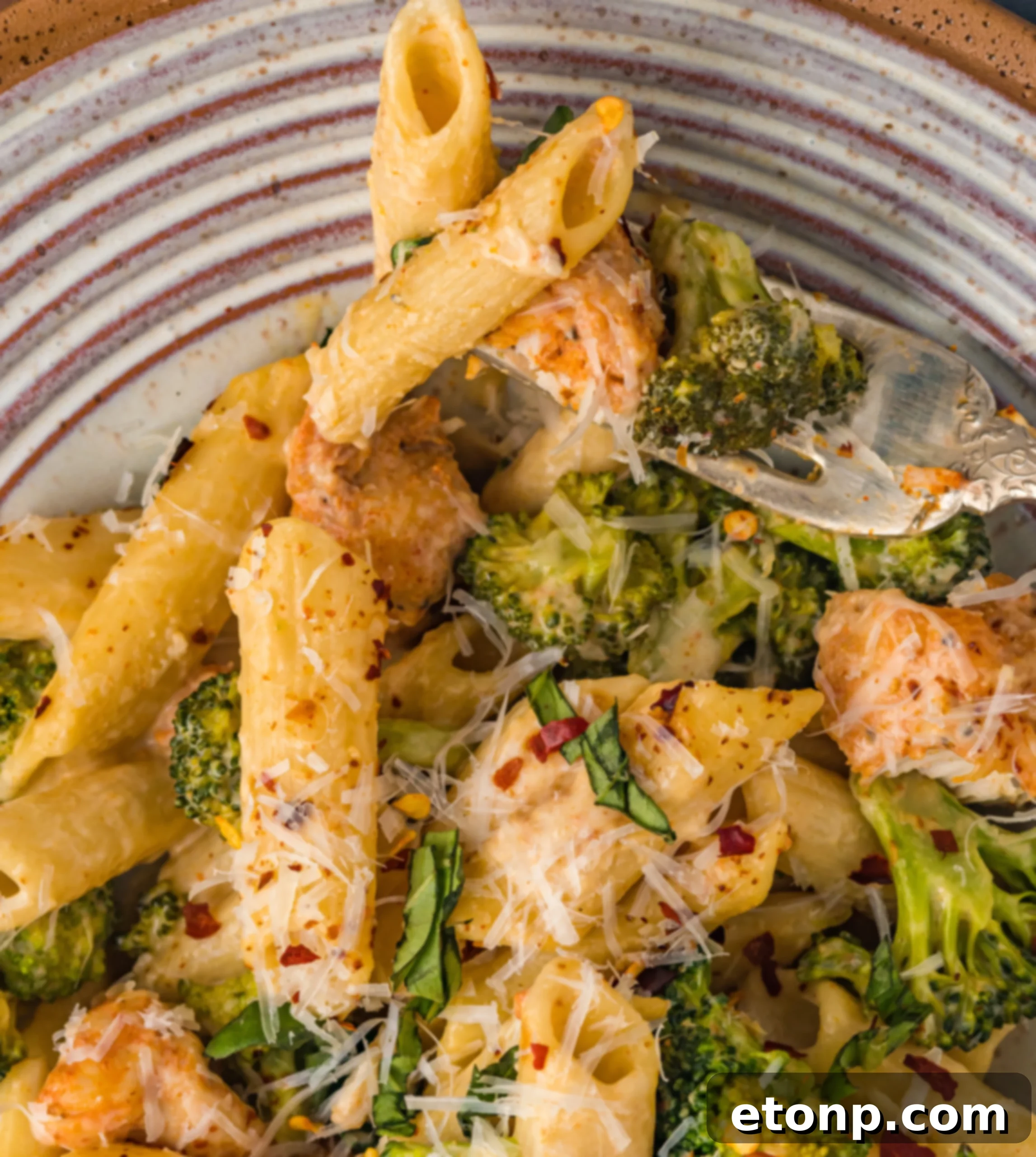 Chicken Pasta Delight 9 A serving of chicken pasta with broccoli on a rustic white plate, garnished with fresh herbs.