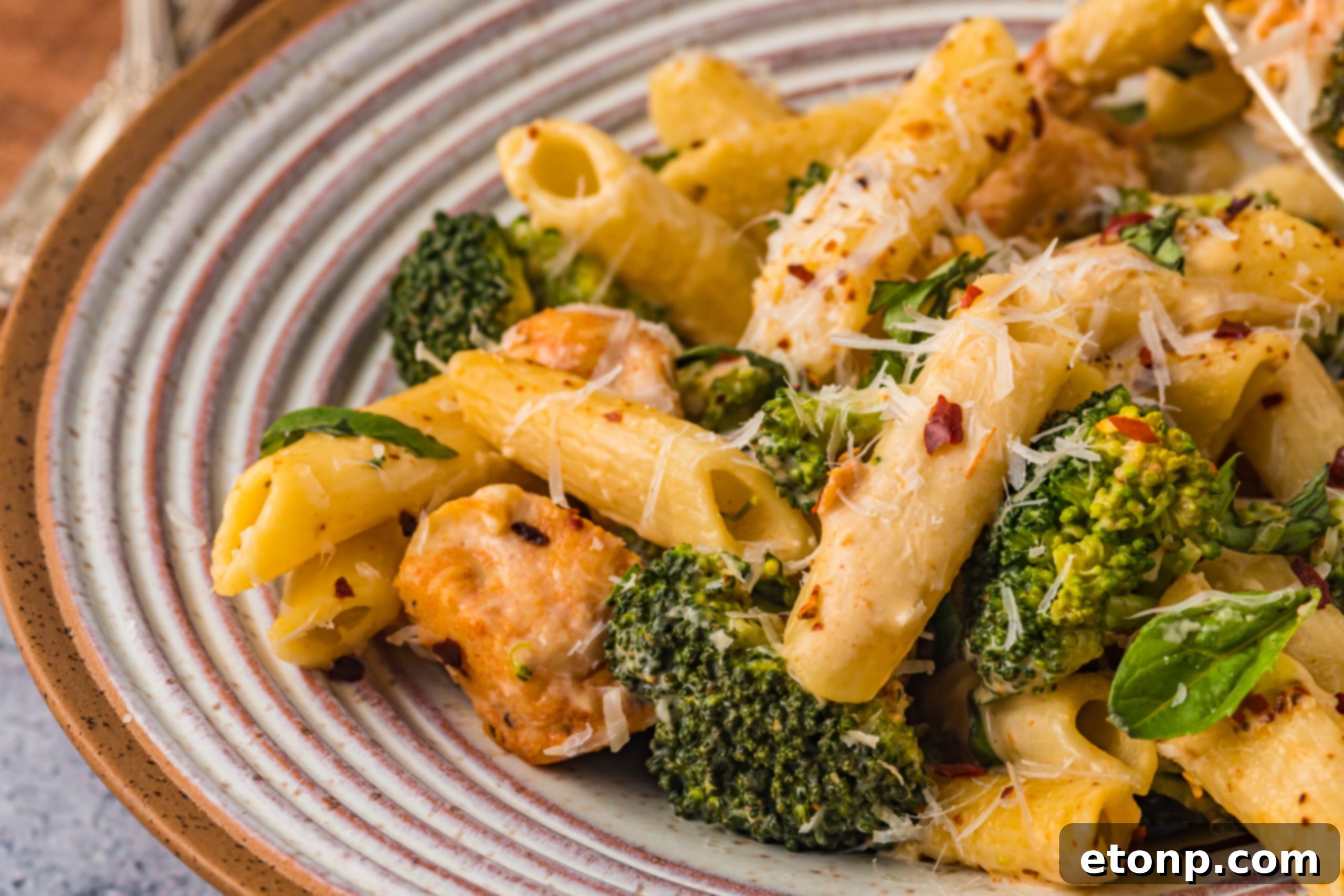 Chicken Pasta Delight 10 A vibrant plate of chicken pasta and broccoli, with a focus on the rich, creamy sauce.