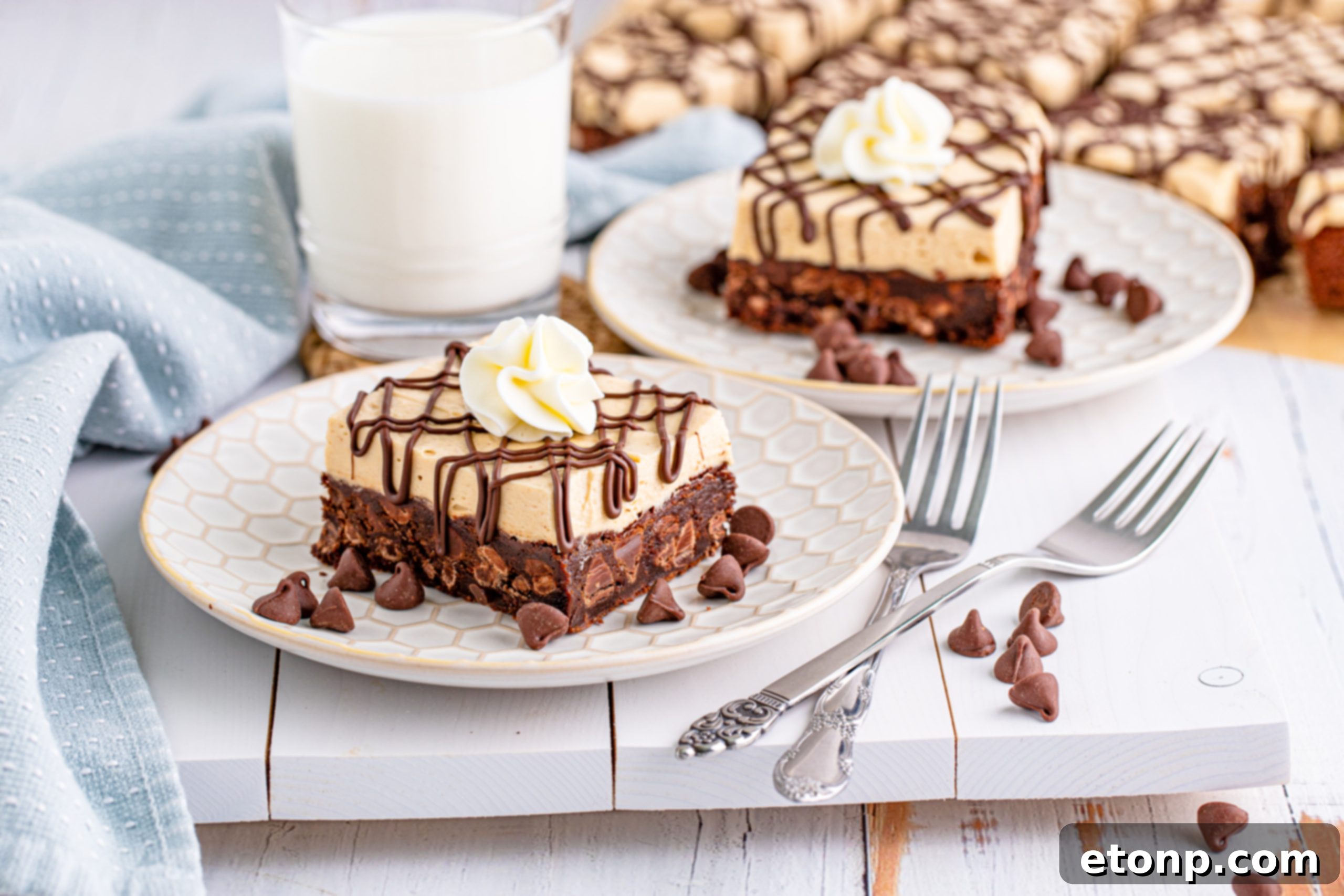 Peanut Butter Brownies on a white plate drizzled with chocolate and topped with whipped cream and a cup of milk