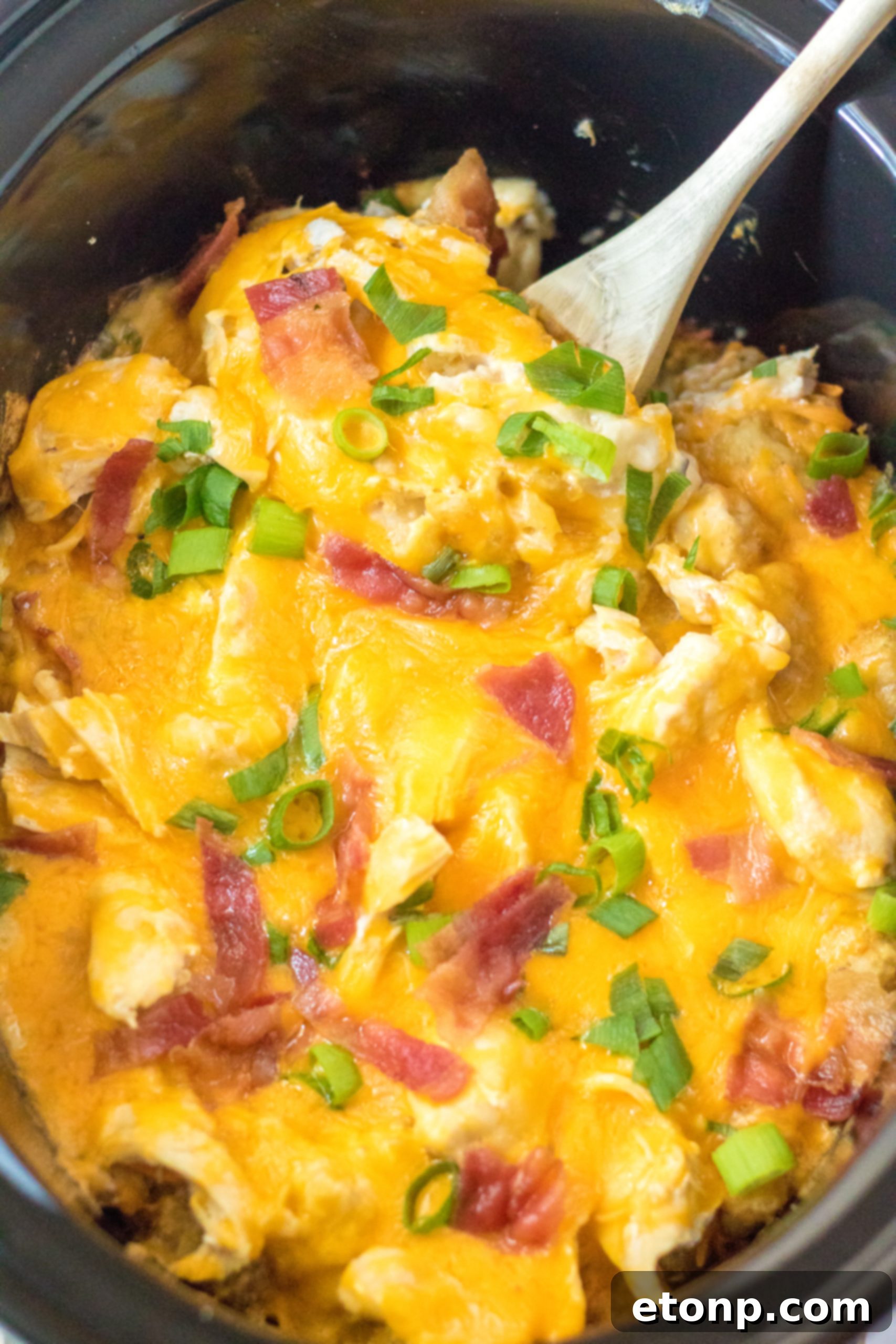 Tater Tot Casserole in the crock pot with a spoon ready to scoop
