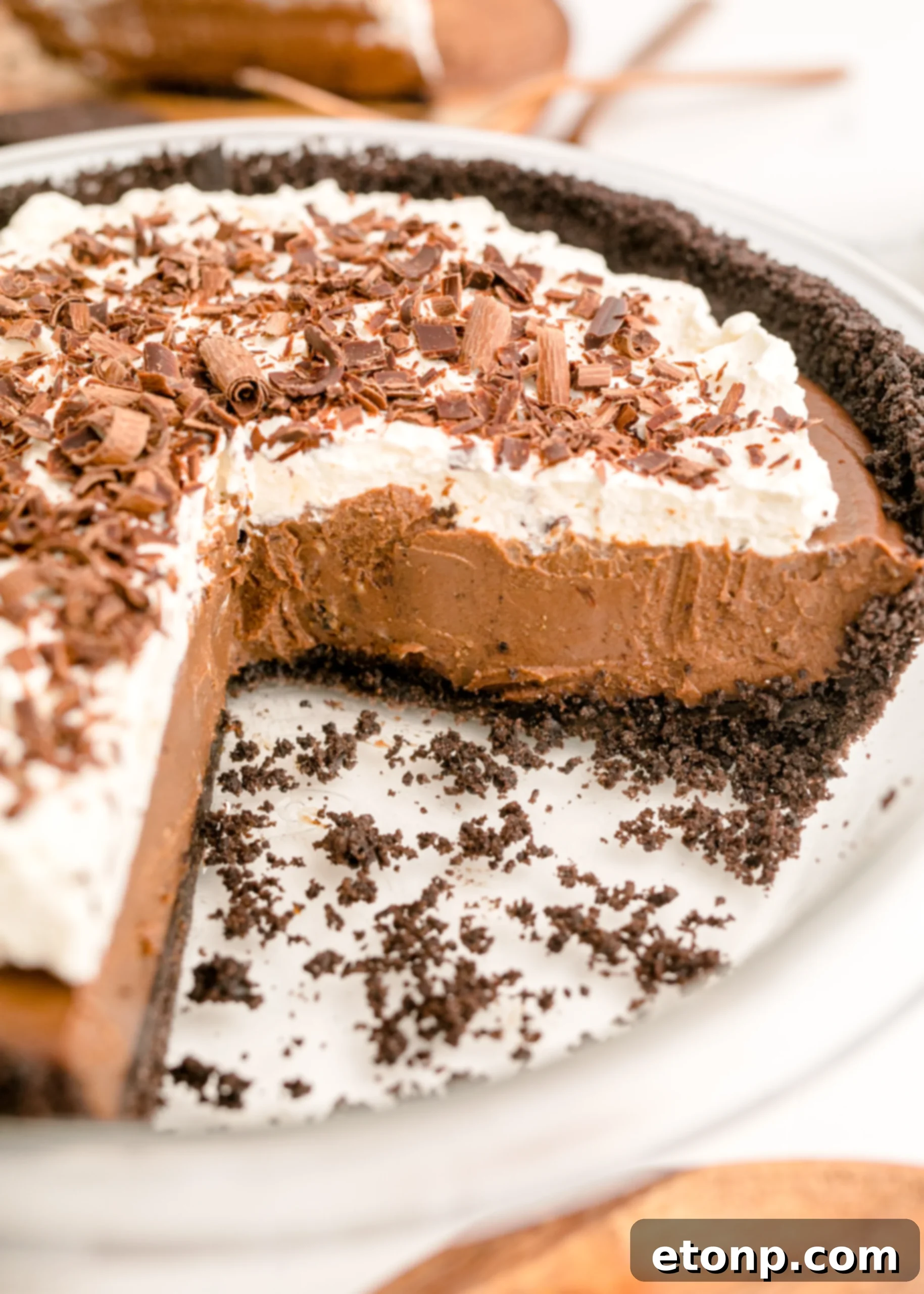 Chocolate Cream Pie topped with whipped cream and chocolate shavings in a white pie plate, presented beautifully