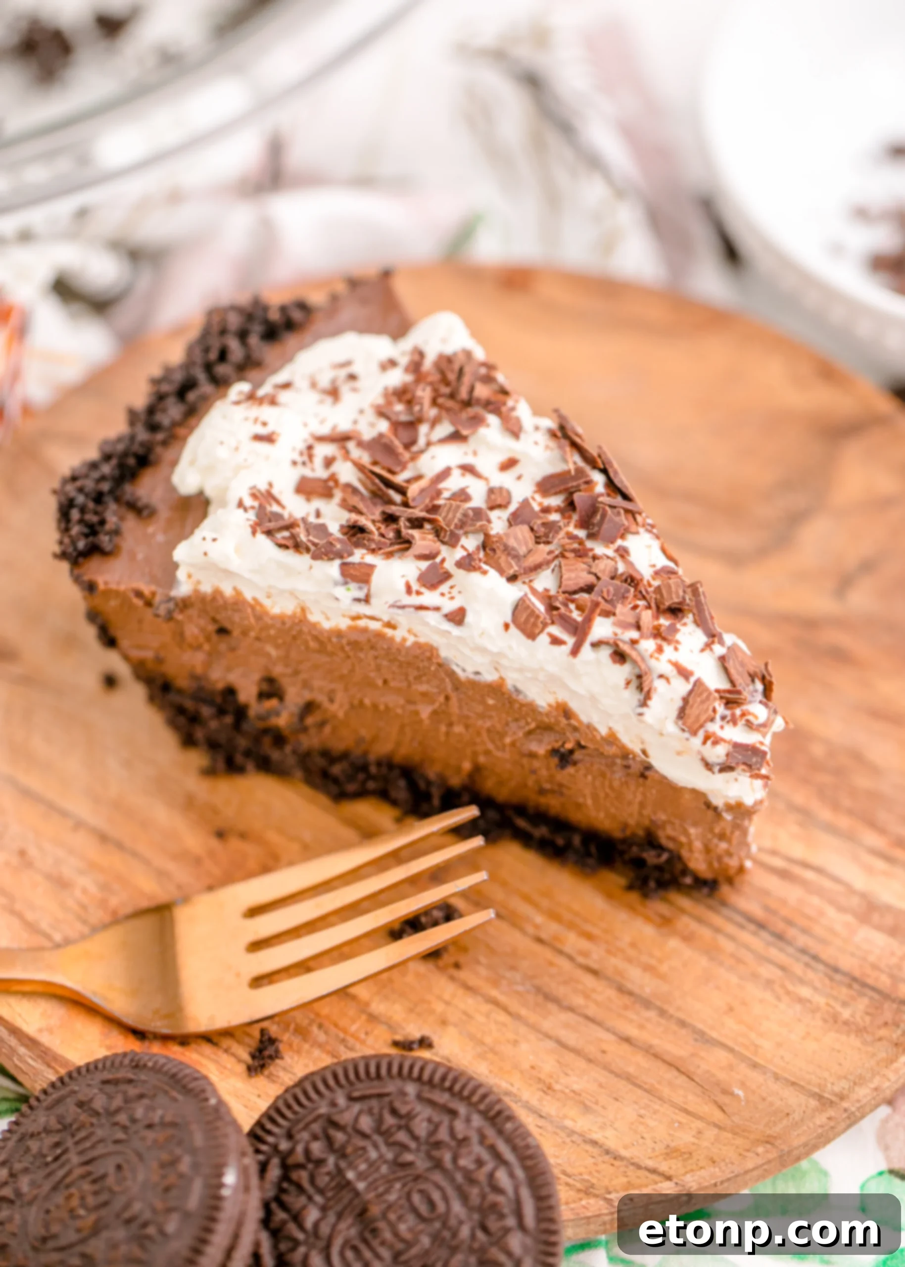 Chocolate Cream Pie topped with whipped cream and chocolate shavings on a rustic brown cutting board