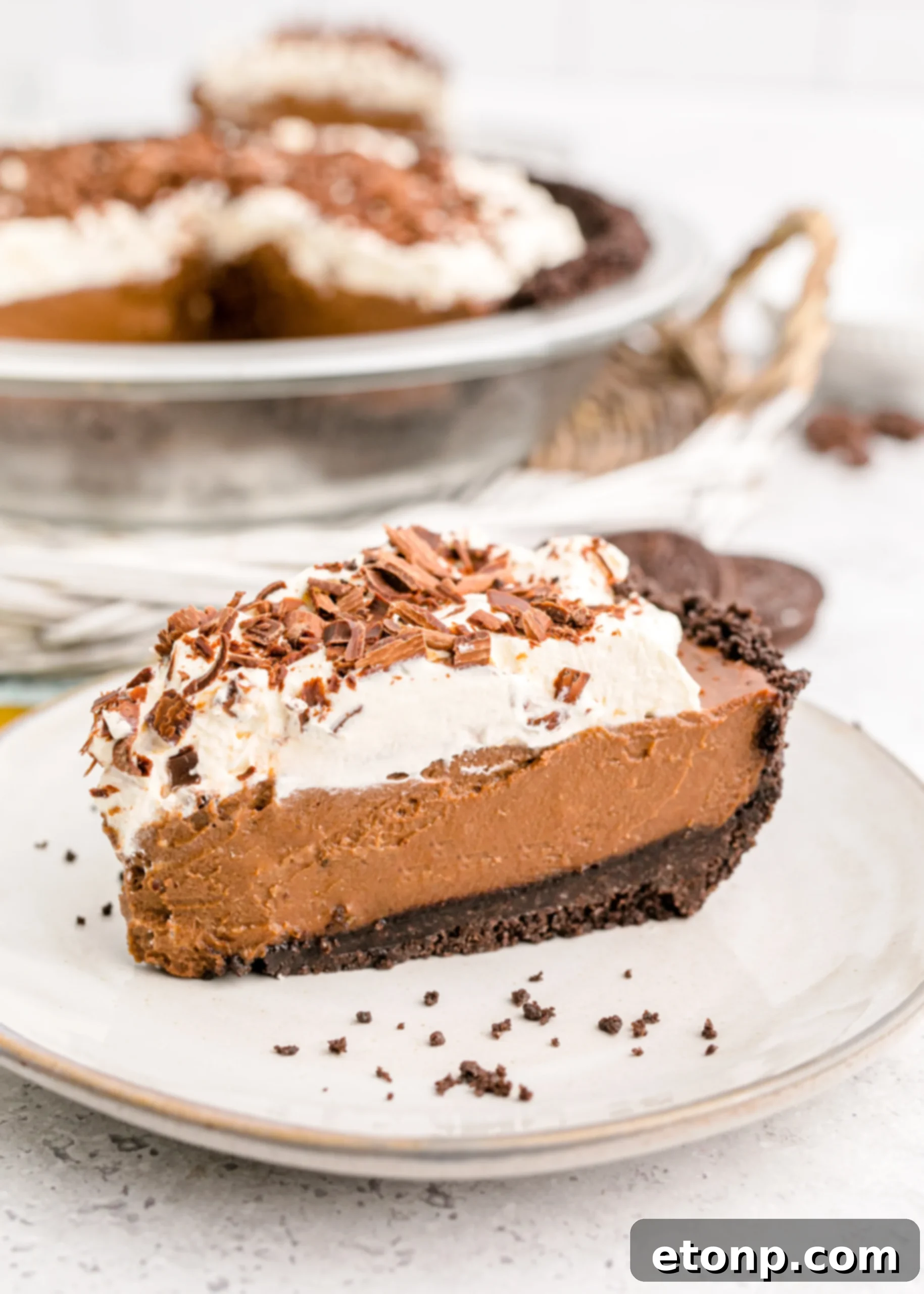 Chocolate Cream Pie topped with whipped cream and chocolate shavings on a white plate, close-up for texture details