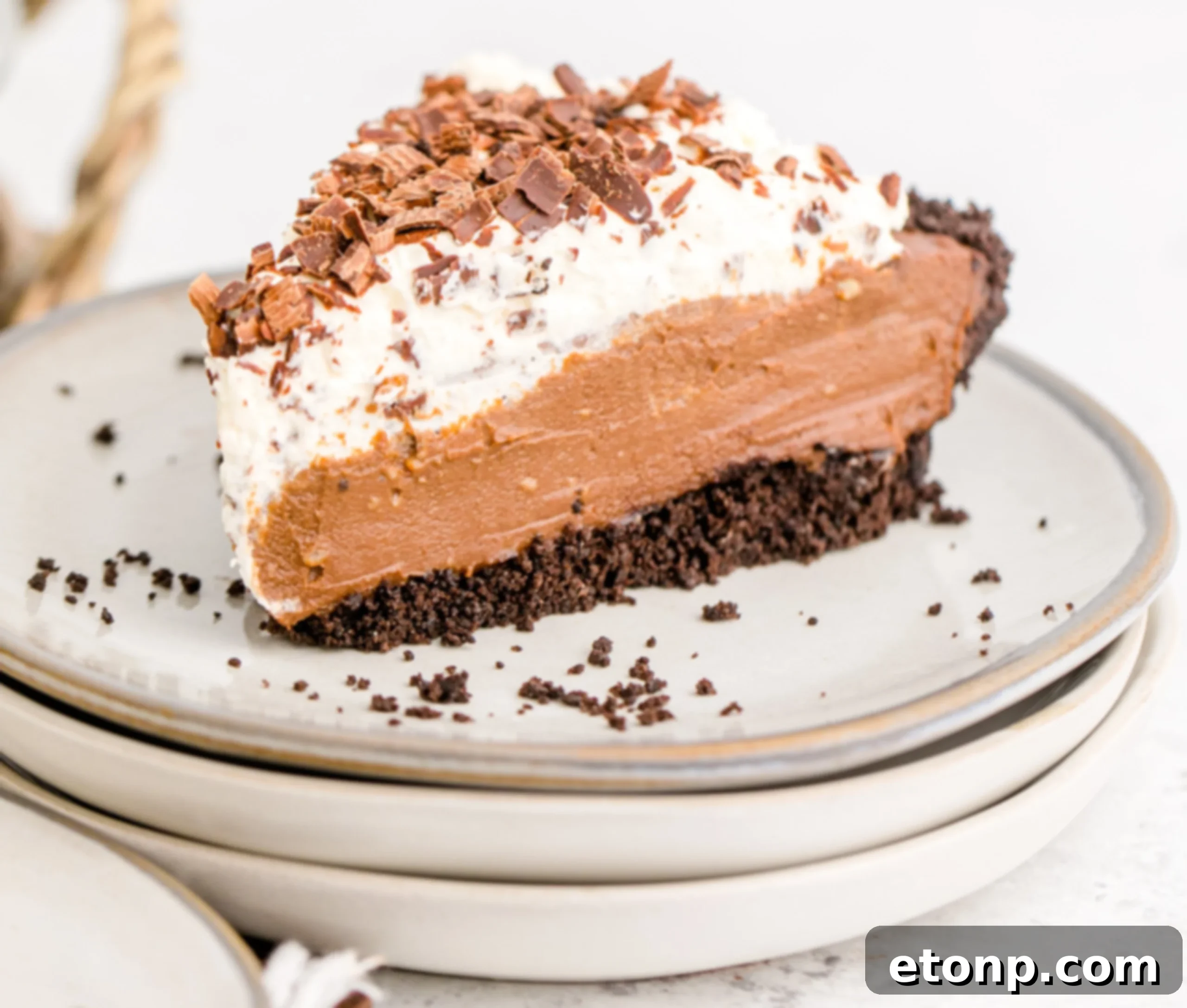 Chocolate Cream Pie topped with whipped cream and chocolate shavings on a white plate, beautifully garnished