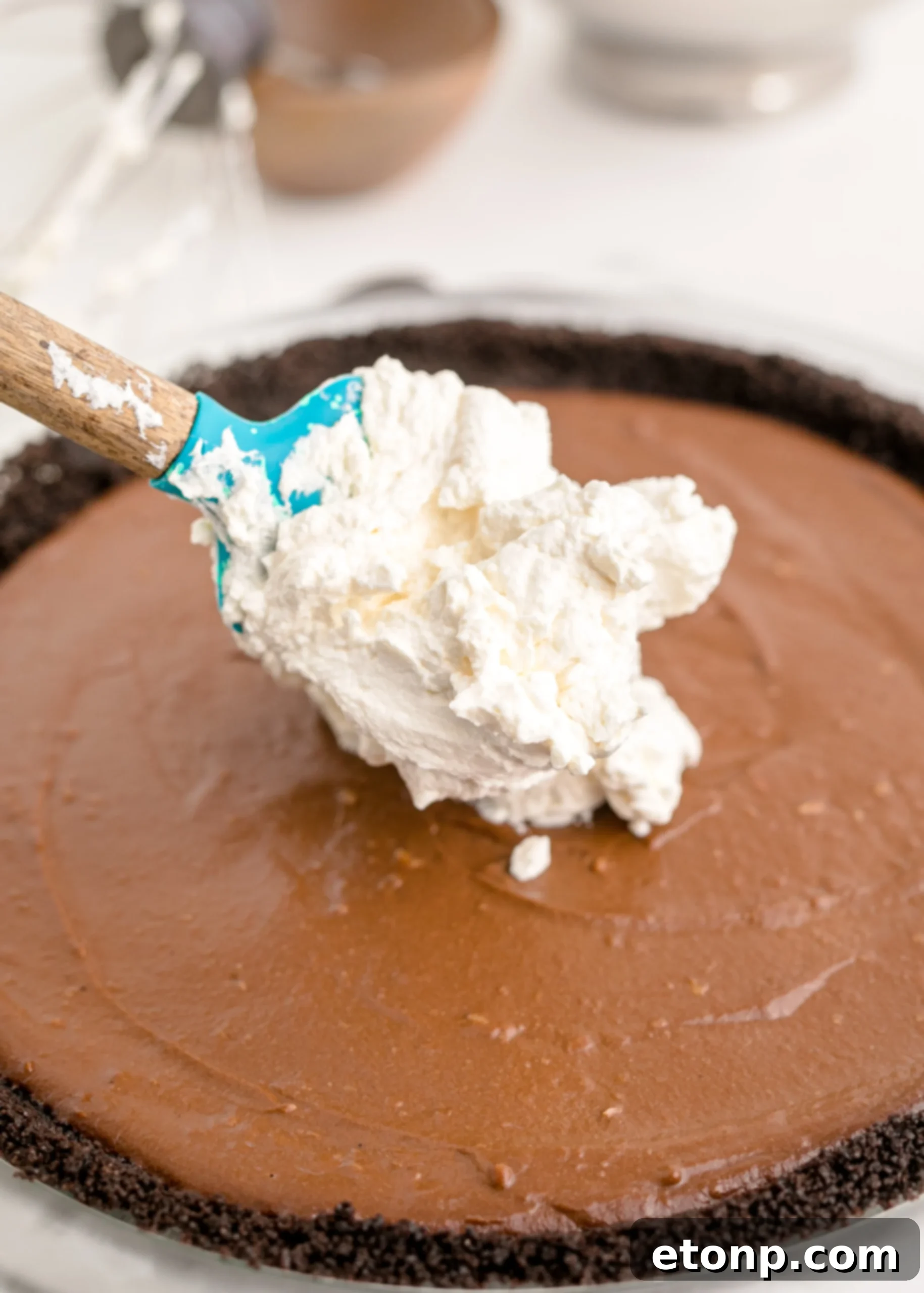 Chocolate Cream Pie with a spoon dropping the luscious whipped cream on top, creating soft peaks