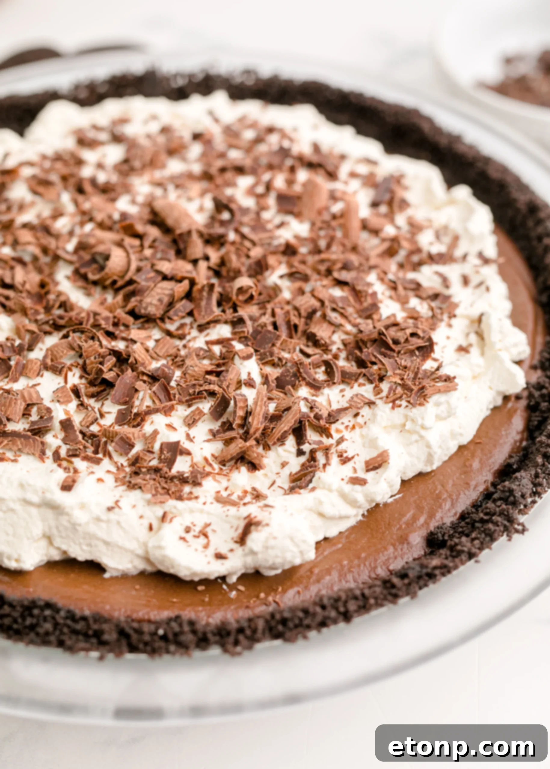 Chocolate Cream Pie topped with real whipped cream and sprinkled with chocolate shavings, captured at an inviting angle