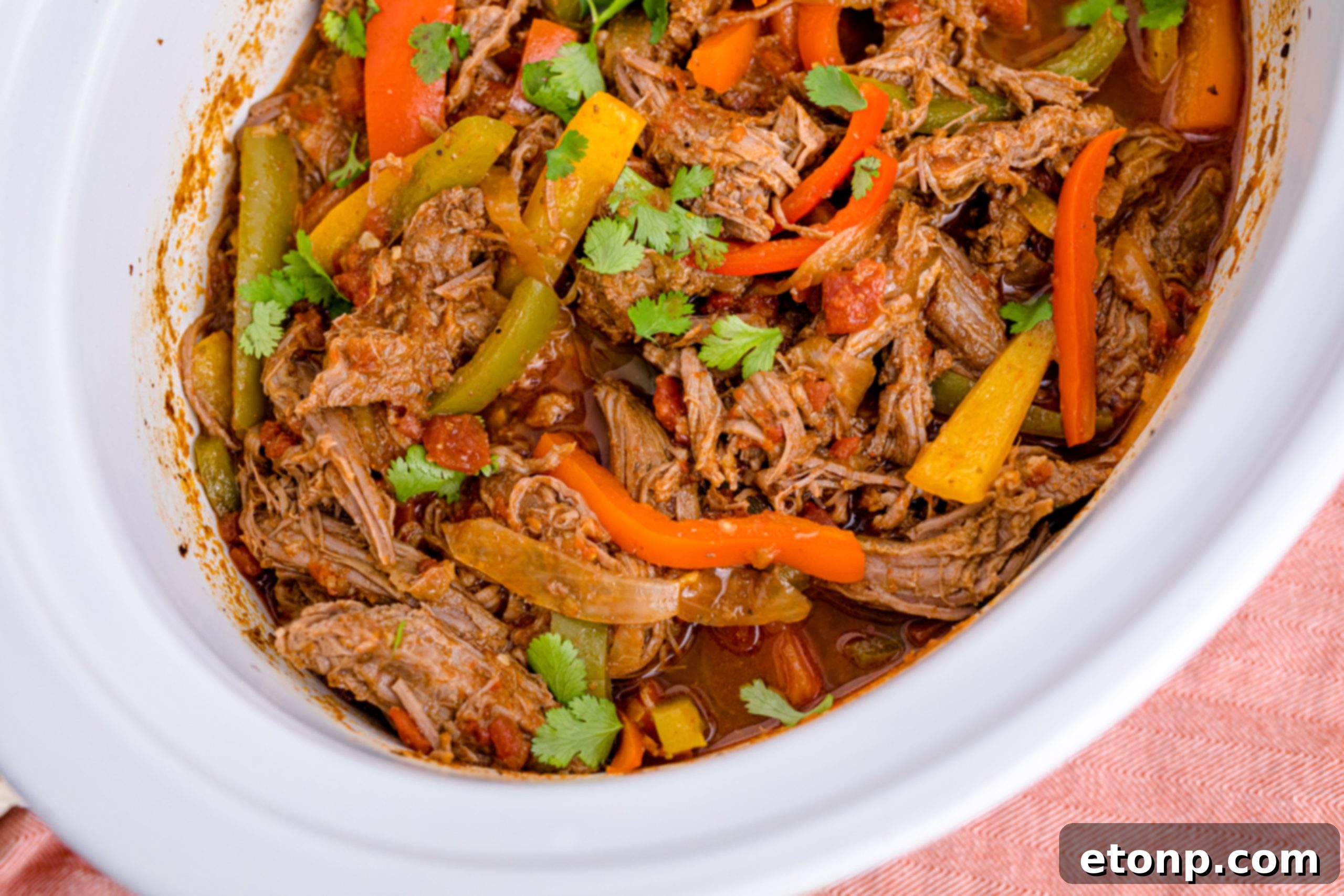 Steak Fajitas in a white crockpit with red and green peppers mixed in
