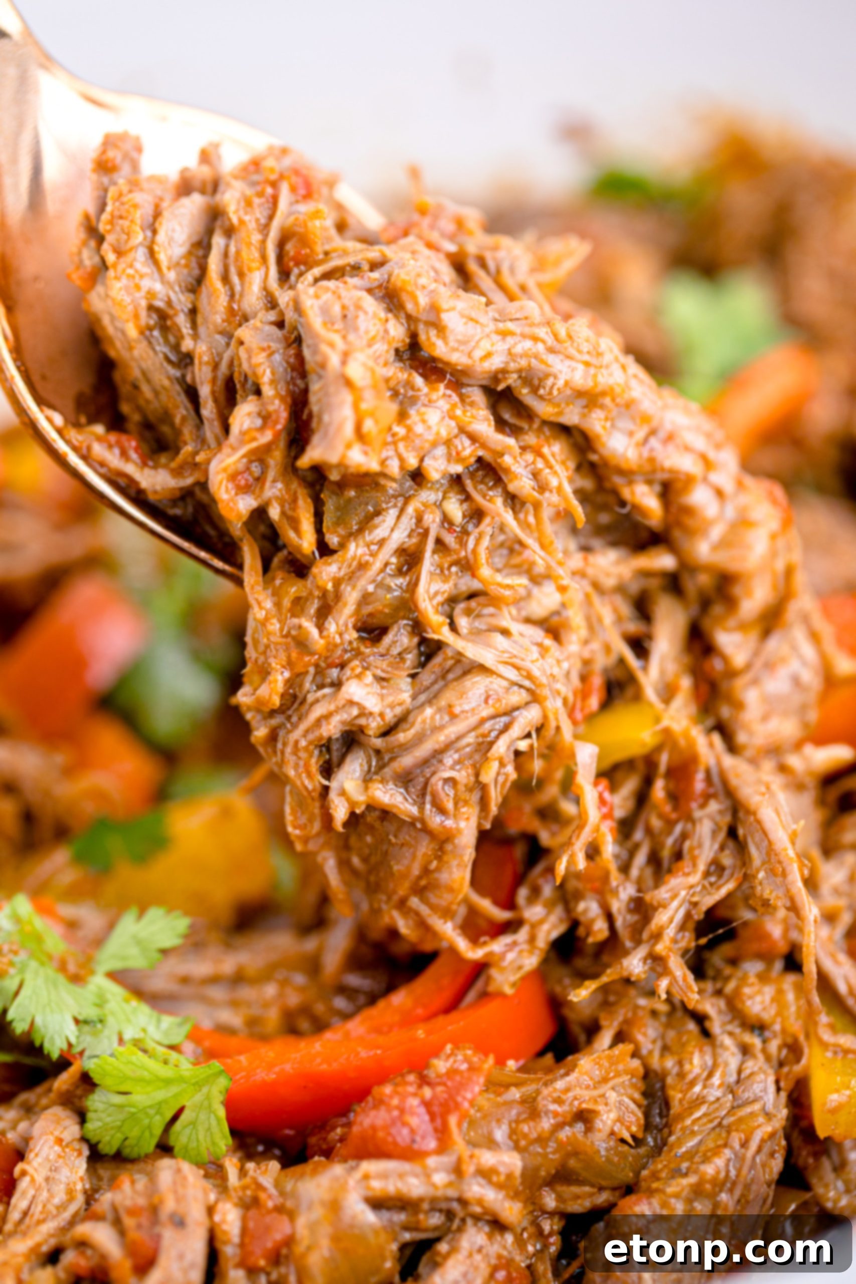 Steak Fajitas in a white crock pot being lifted with a spoon