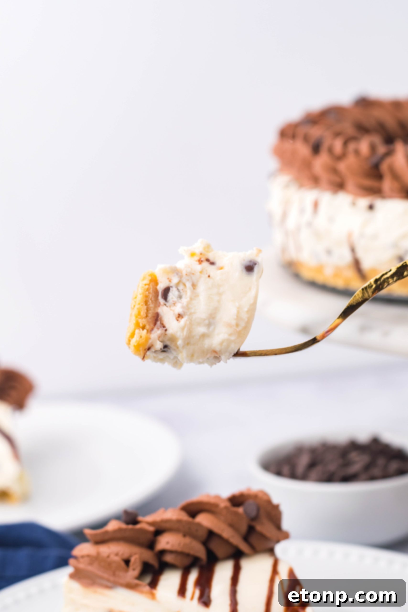 A close-up shot of a bite of Chocolate Chip Cheesecake on a gold fork.