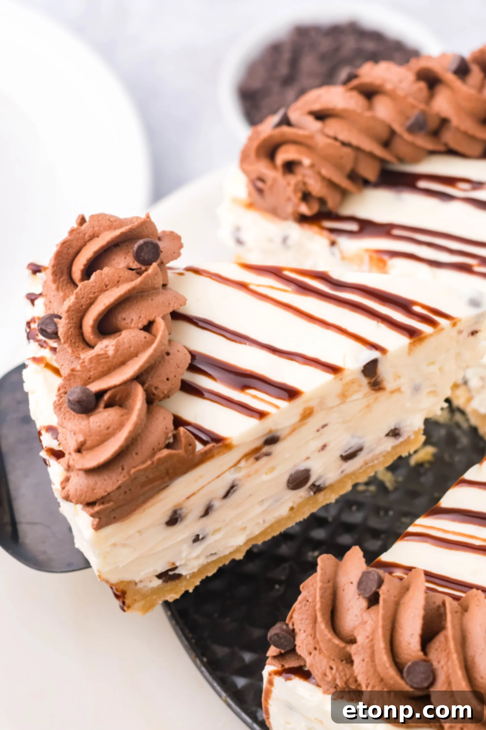 A slice of Chocolate Chip Cheesecake being lifted from a baking pan with a black spatula.